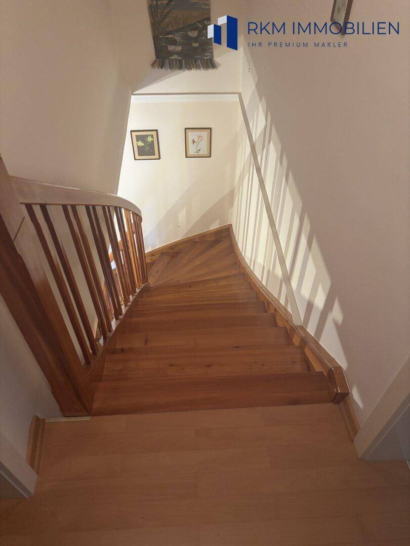 Holztreppe mit Geländer, die die verschiedenen Etagen des Hauses miteinander verbindet.