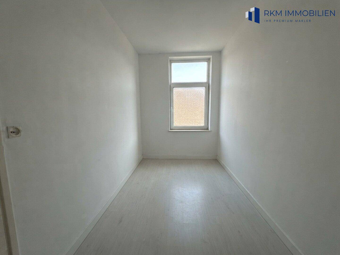 Kleines, helles Zimmer mit einem Fenster und hellem Boden, geeignet als Schlaf- oder Arbeitszimmer in der Wohnung.