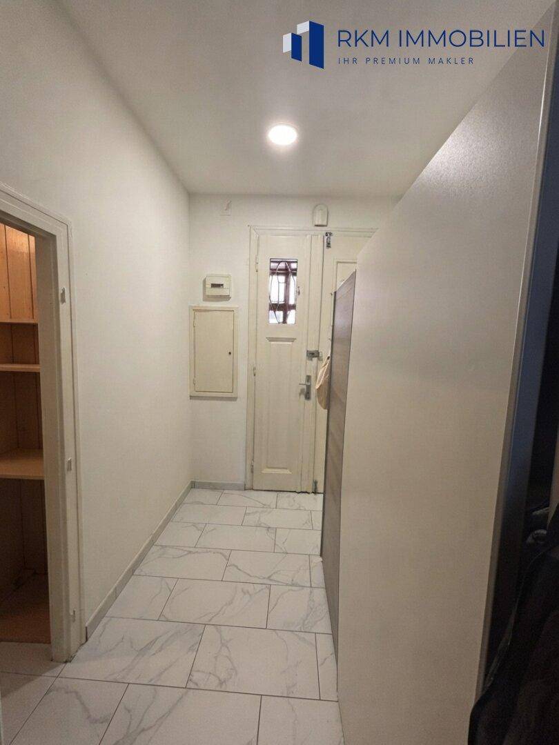 Heller Flur mit modernen Fliesen und Zugang zu verschiedenen Räumen der Wohnung, gut gepflegt.