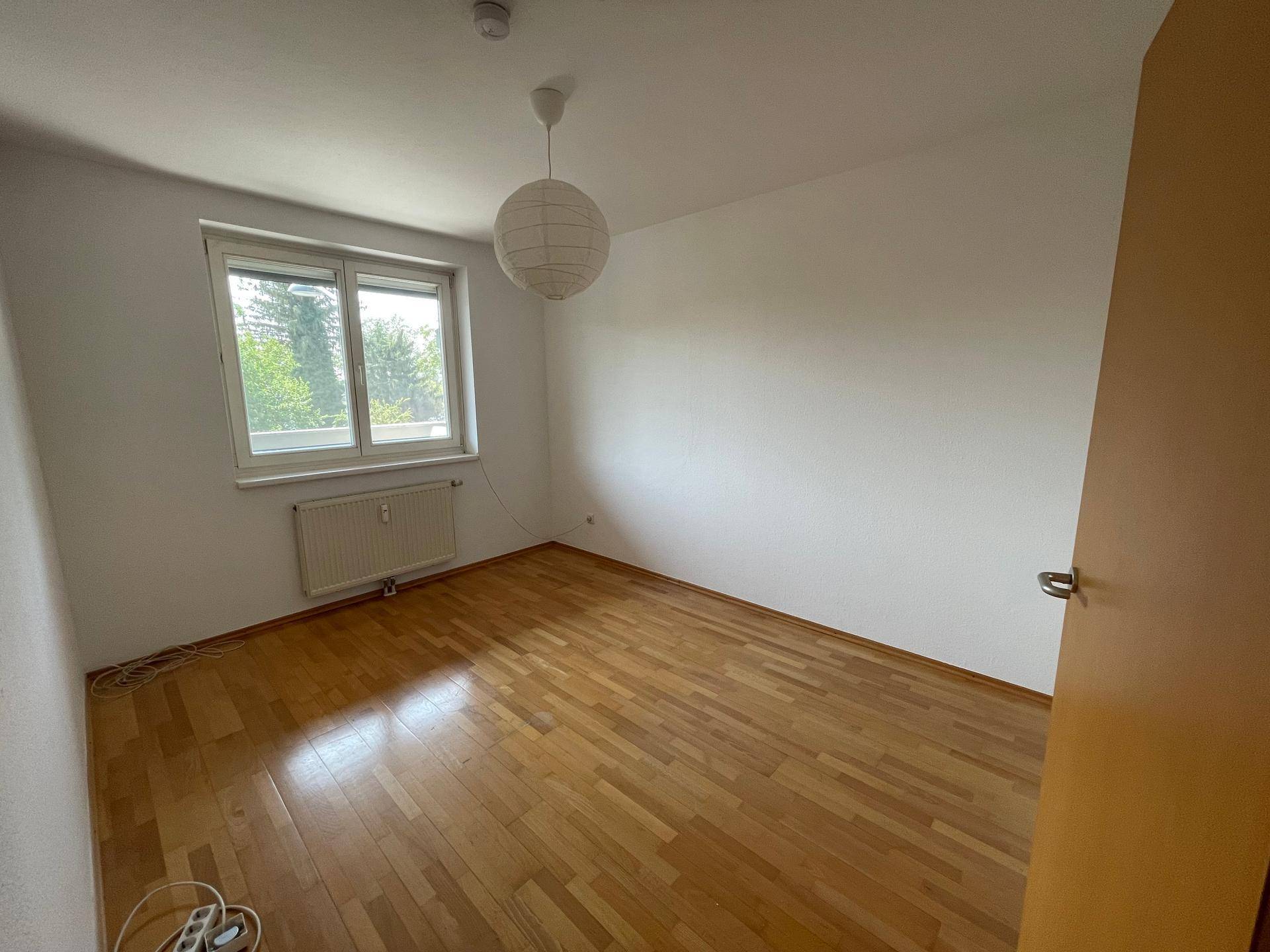 Helles Zimmer mit Holzfußboden und Fenster, bietet viel natürliches Licht und eine freundliche Ausstrahlung.