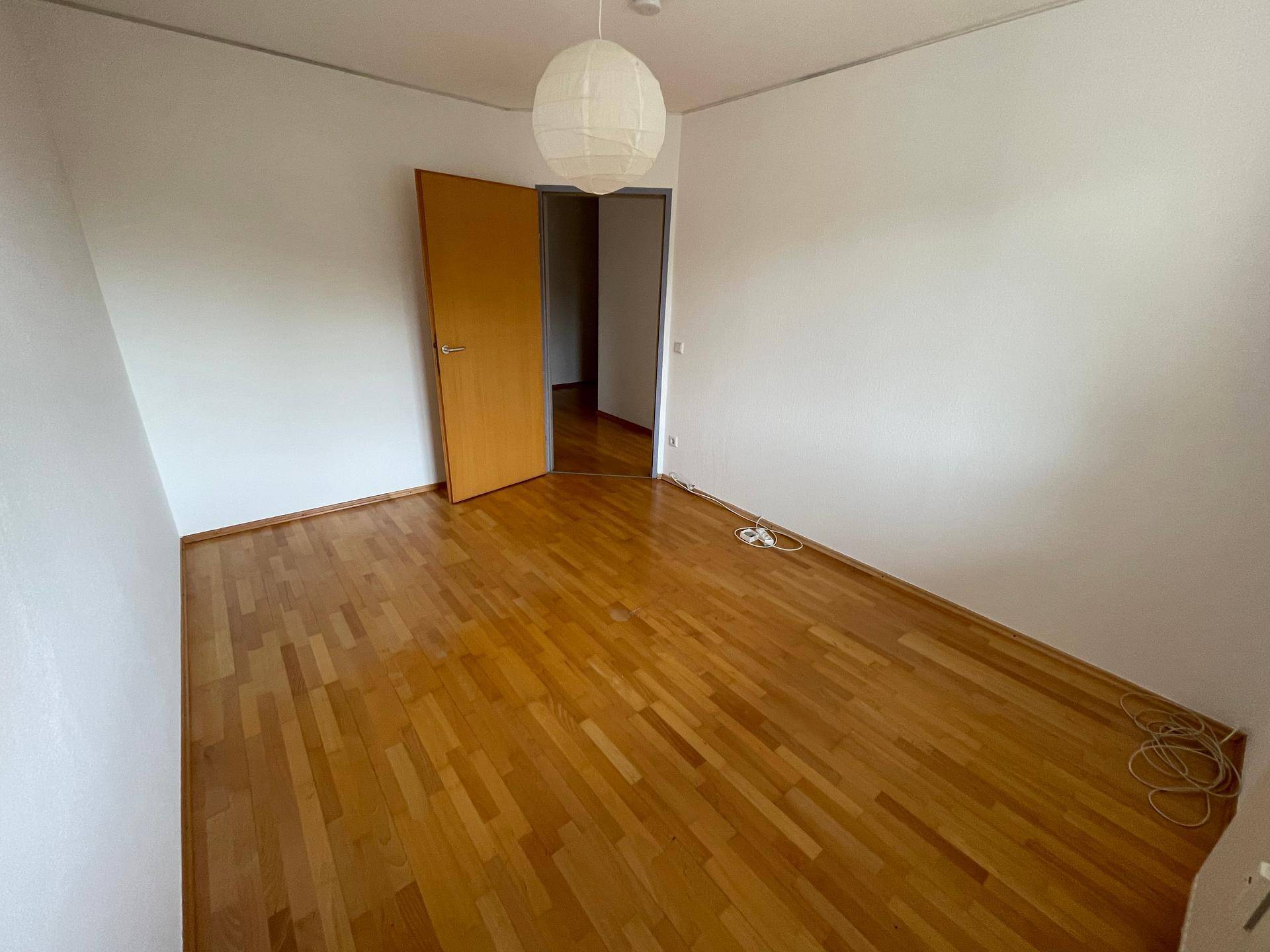 Geräumiges Zimmer mit Holzfußboden und weiß gestrichenen Wänden, bietet eine neutrale Basis.