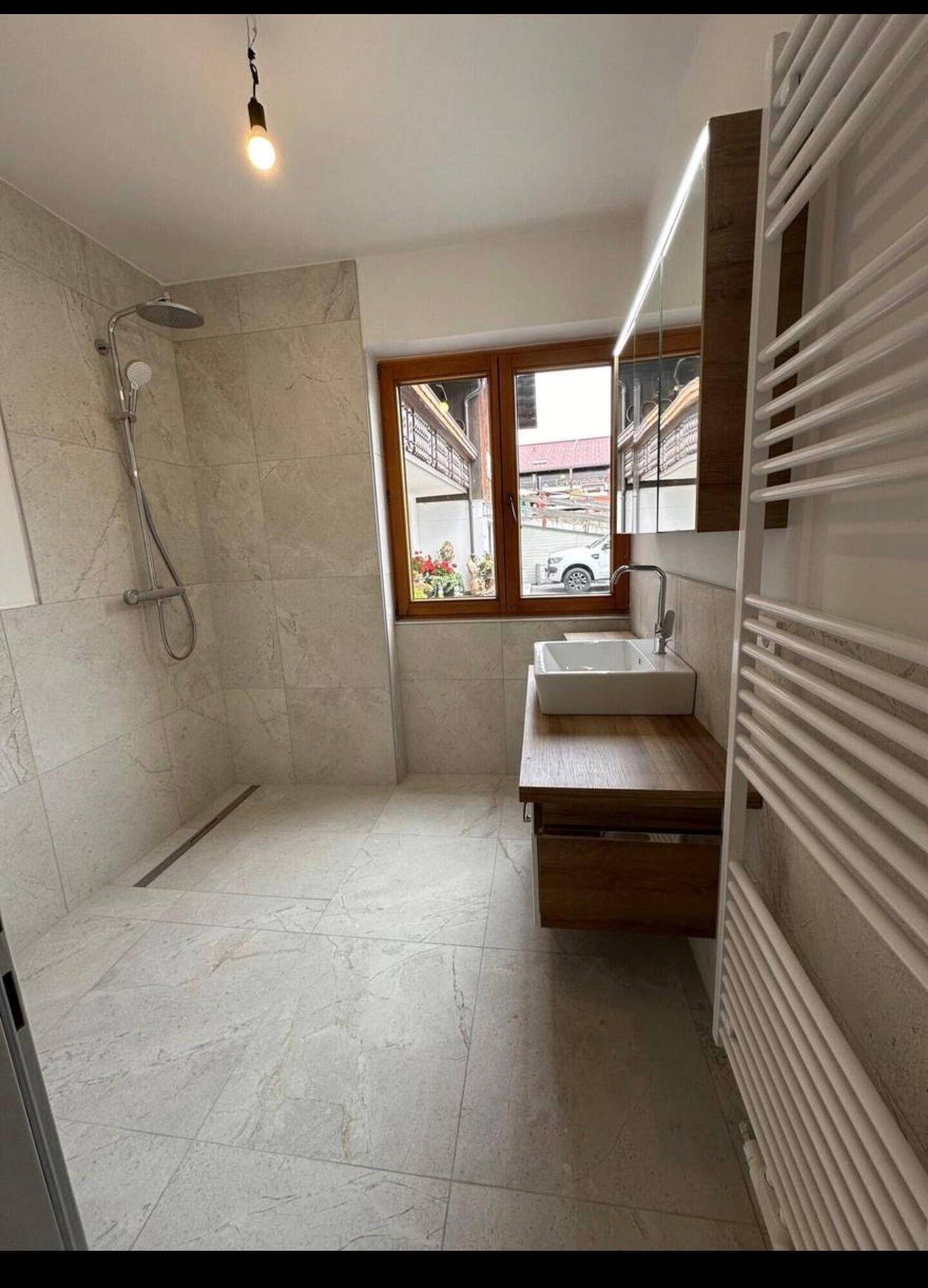 Modernes Badezimmer mit begehbarer Dusche, Waschbecken und Fenster für natürliches Licht.