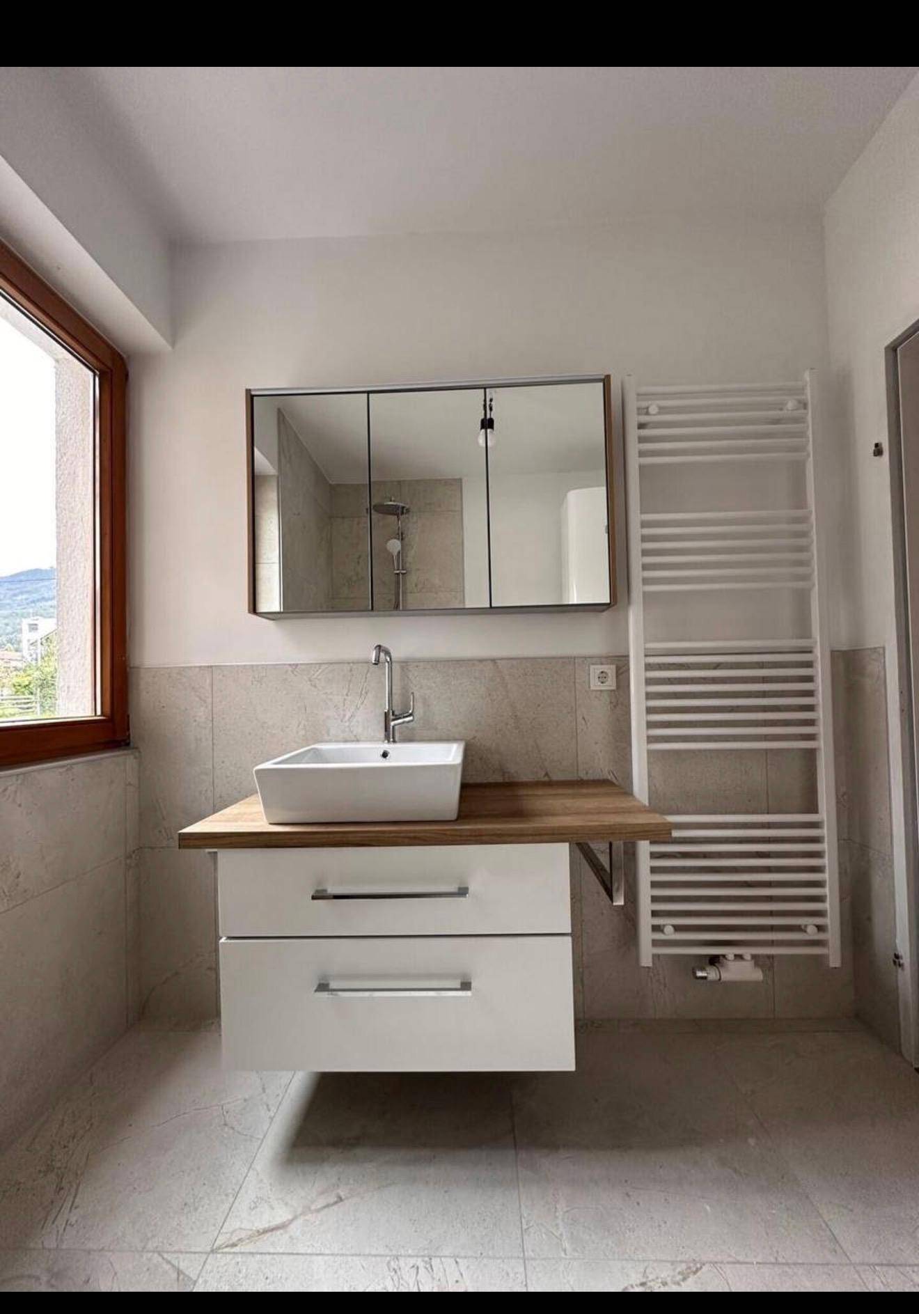 Modernes Badezimmer mit schwebendem Waschtisch, Spiegelschrank und beheiztem Handtuchhalter.