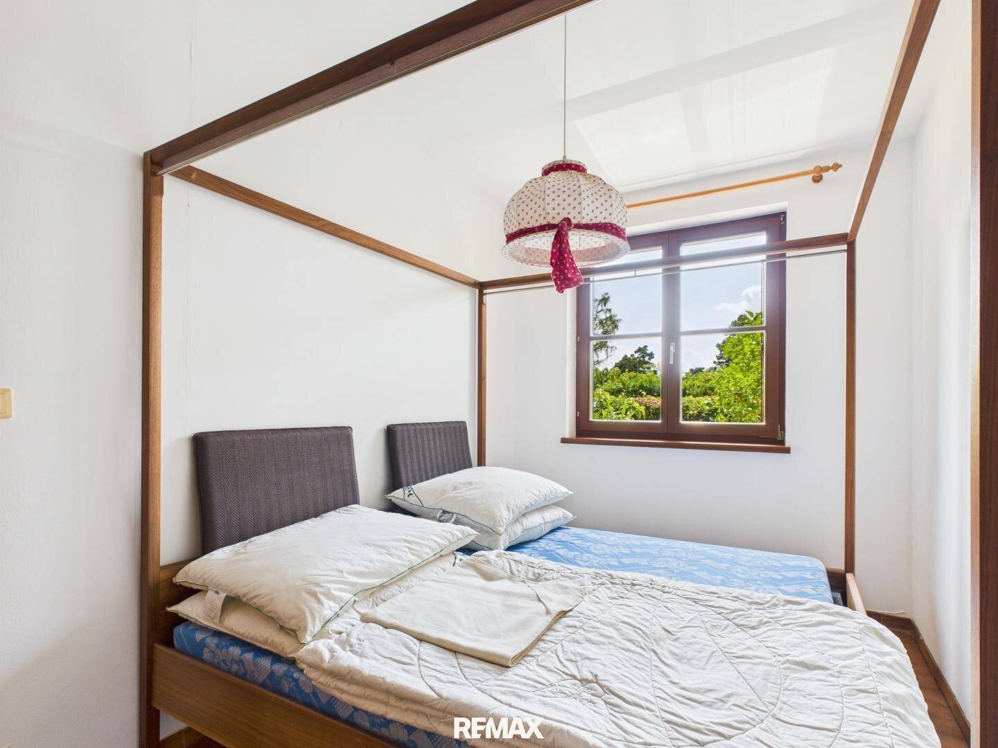 Schlafzimmer mit zwei Einzelbetten, einem Fenster und einem schönen Blick ins Grüne.