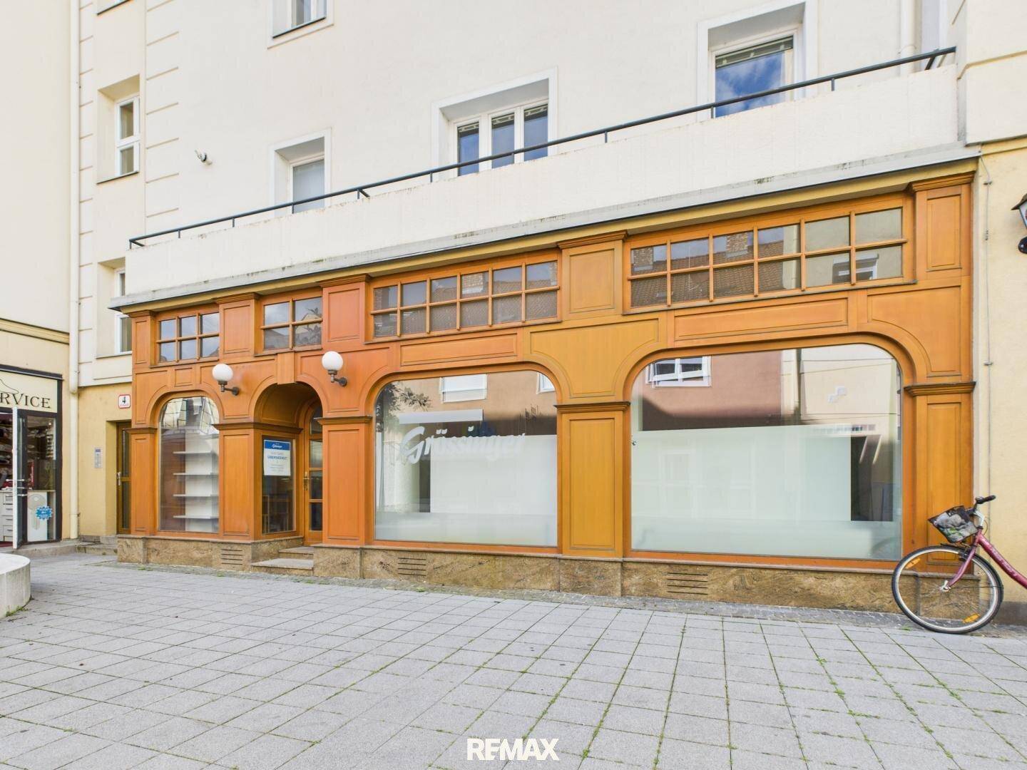 Attraktive Geschäftsfassade mit großen Schaufenstern und Holzelementen an einem sonnigen Tag.
