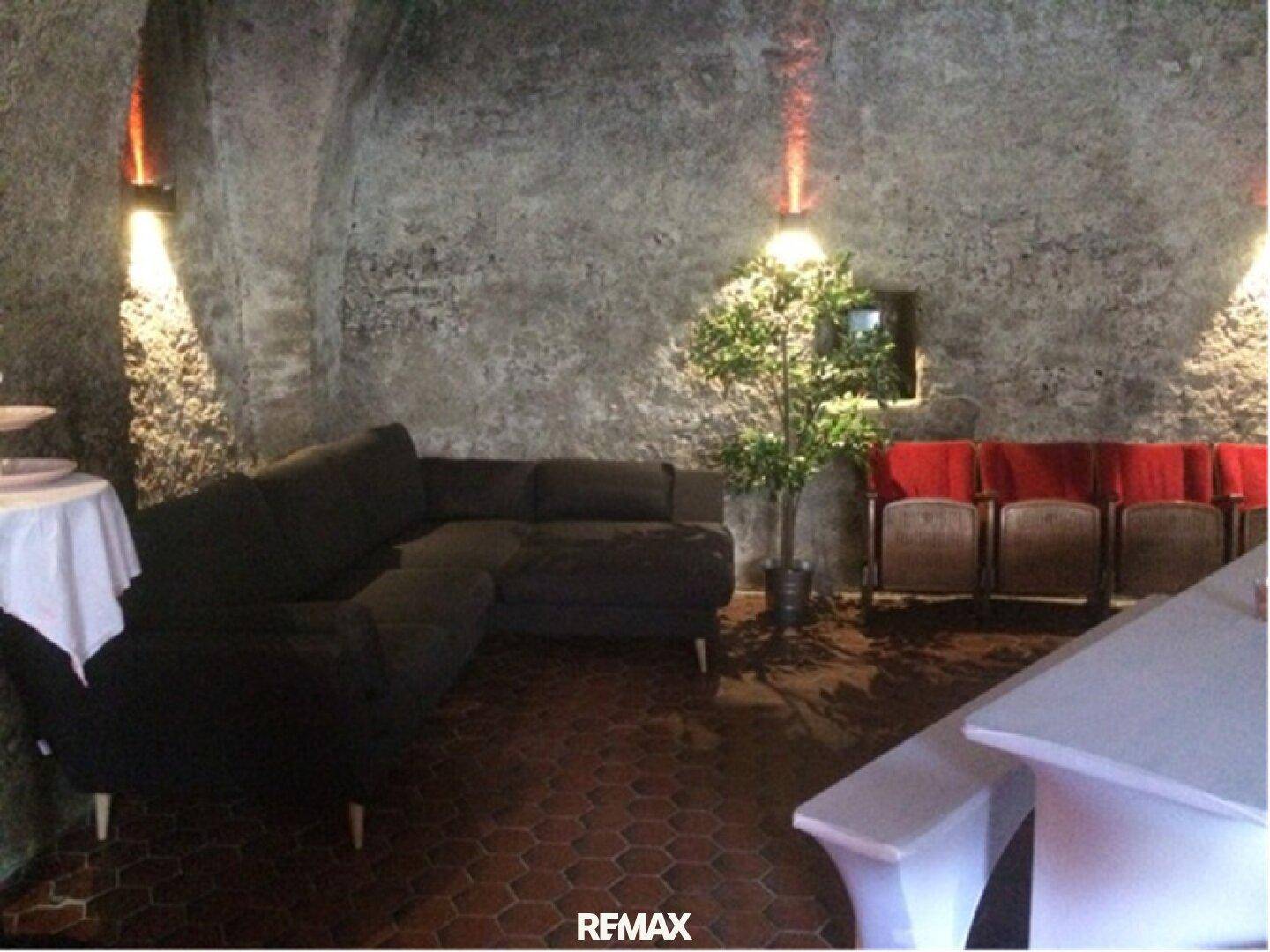 Rustikaler Lounge-Bereich in einem Gewölbekeller mit Steinfliesenboden, Sofa und indirekter Beleuchtung.