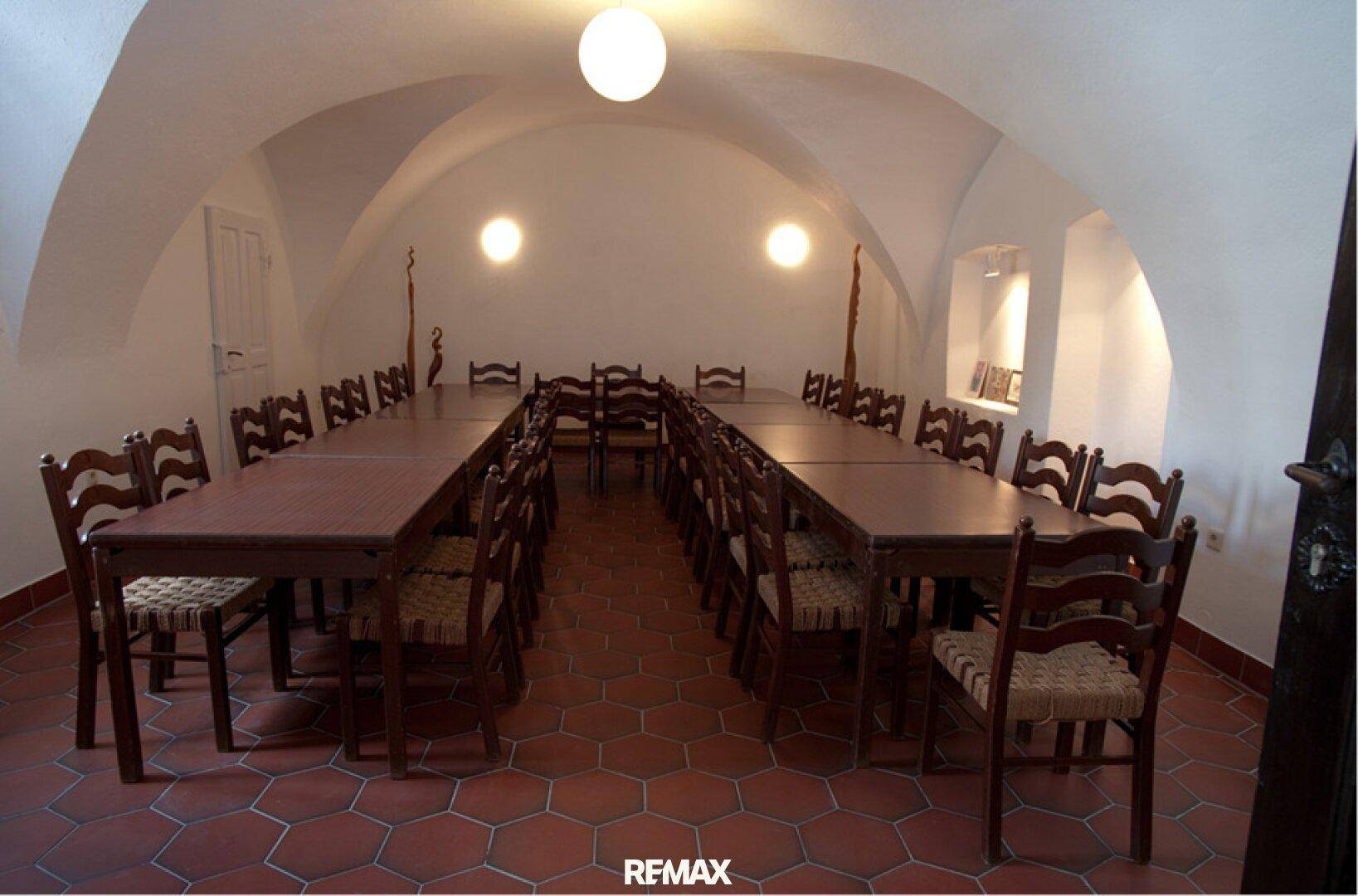 Langer Speisesaal in einem Gewölbekeller mit Holztischen und Stühlen, ideal für größere Gruppen.