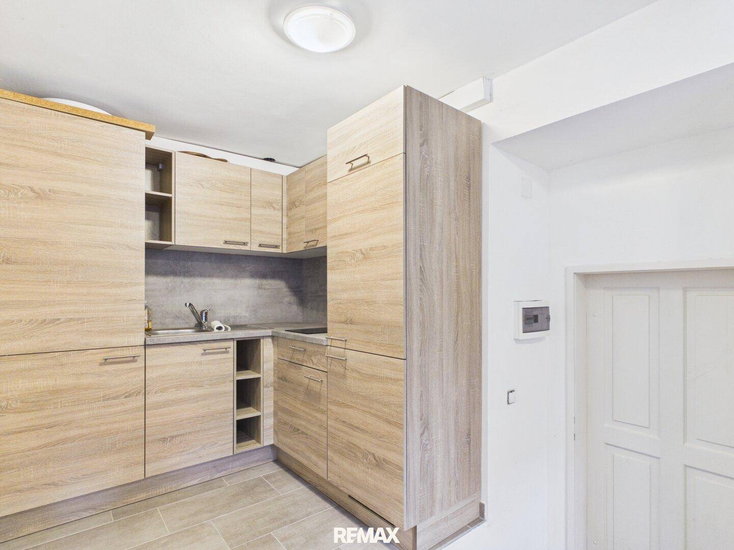 Moderne Küchenzeile mit Holzoptik-Fronten und integriertem Spülbecken in hellem Raum.