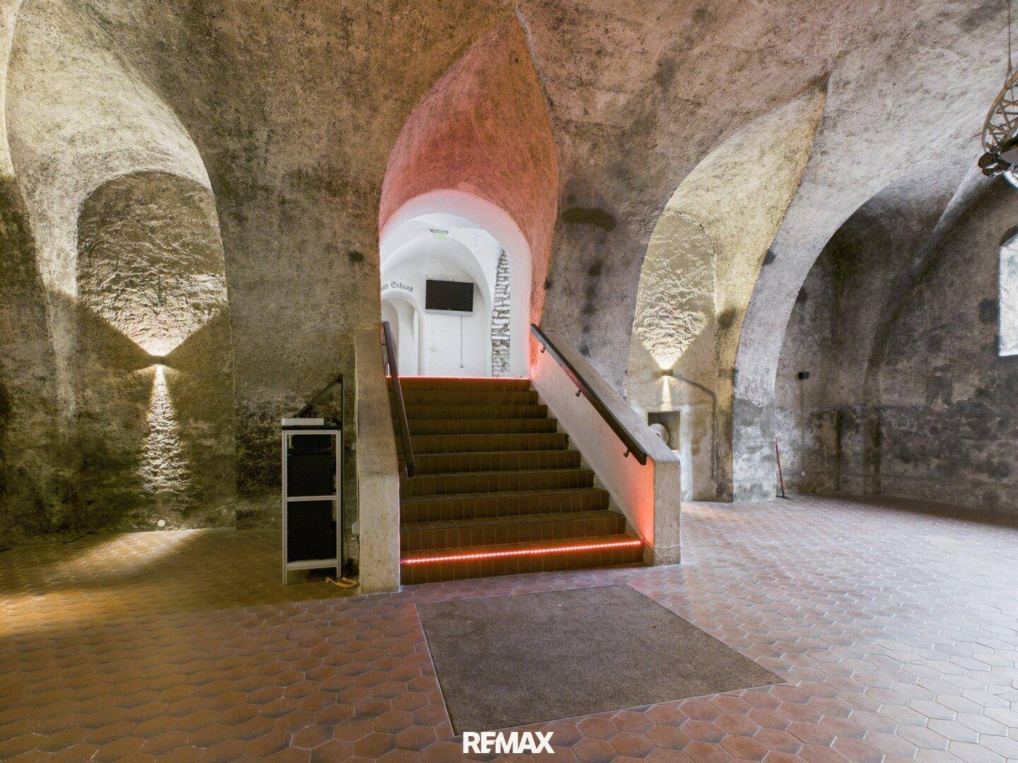 Historischer Gewölbekeller mit Steintreppe, moderner Beleuchtung und rustikalem Ambiente, ideal für Events.