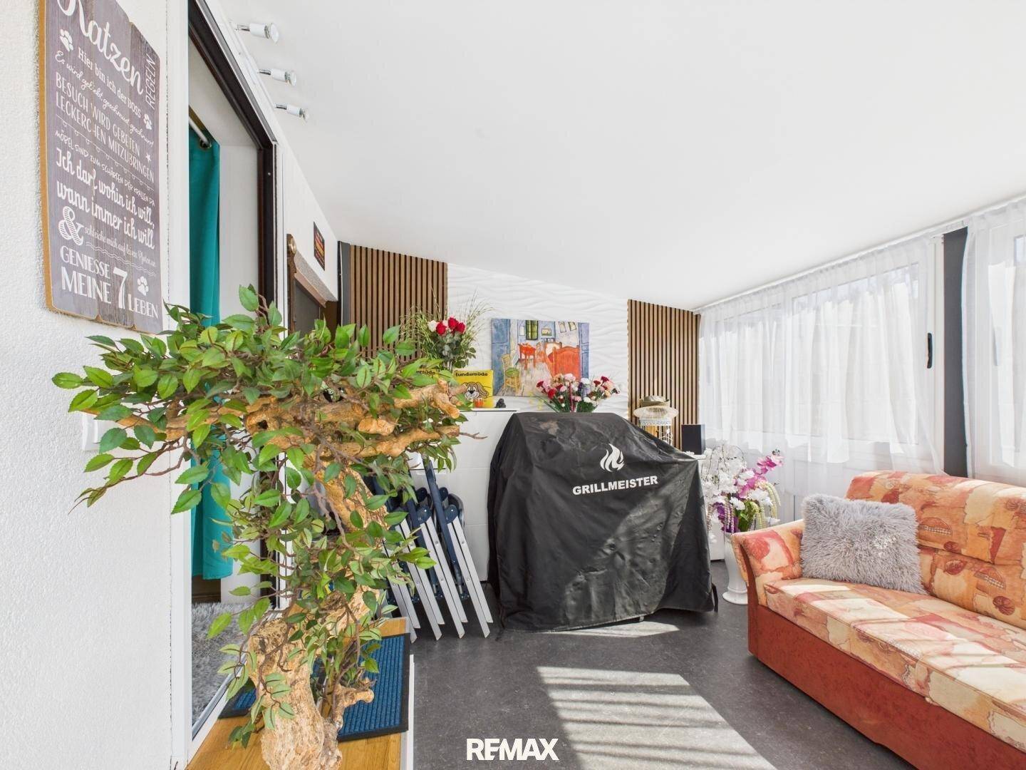 Heller, verglaster Wintergarten mit bequemer Couch und Grill, ideal für entspannte Stunden.