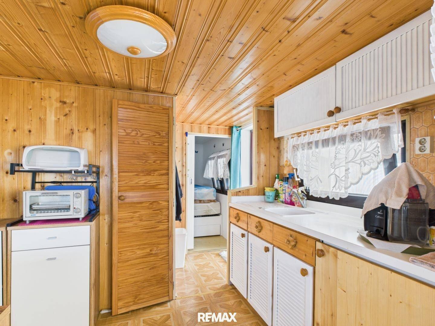 Funktionale Küchenzeile mit Spülbecken, Arbeitsfläche und Holzverkleidung im Landhausstil.