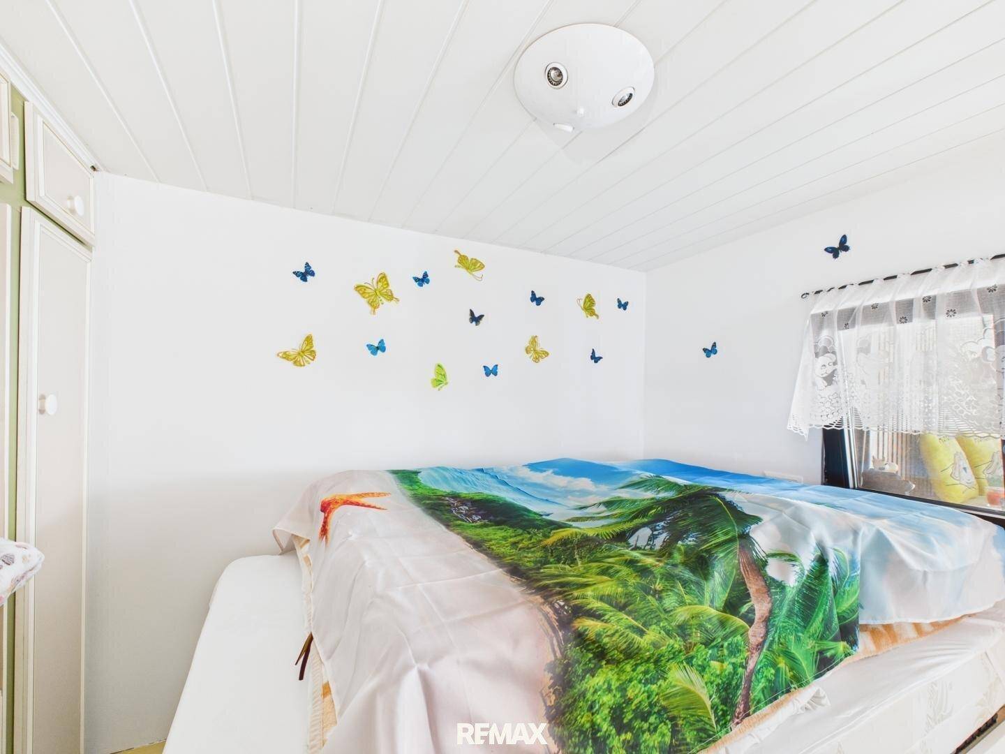 Helles Schlafzimmer mit Einzelbett, Schmetterlingsdekoration und weißer Deckenverkleidung.