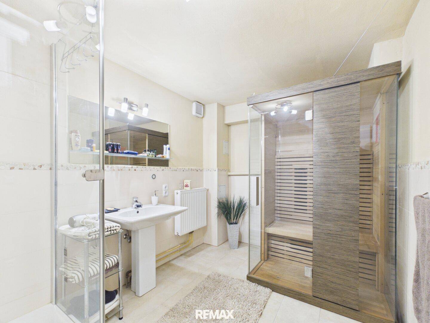 Modernes Badezimmer mit Duschkabine, Waschbecken und integrierter Sauna.