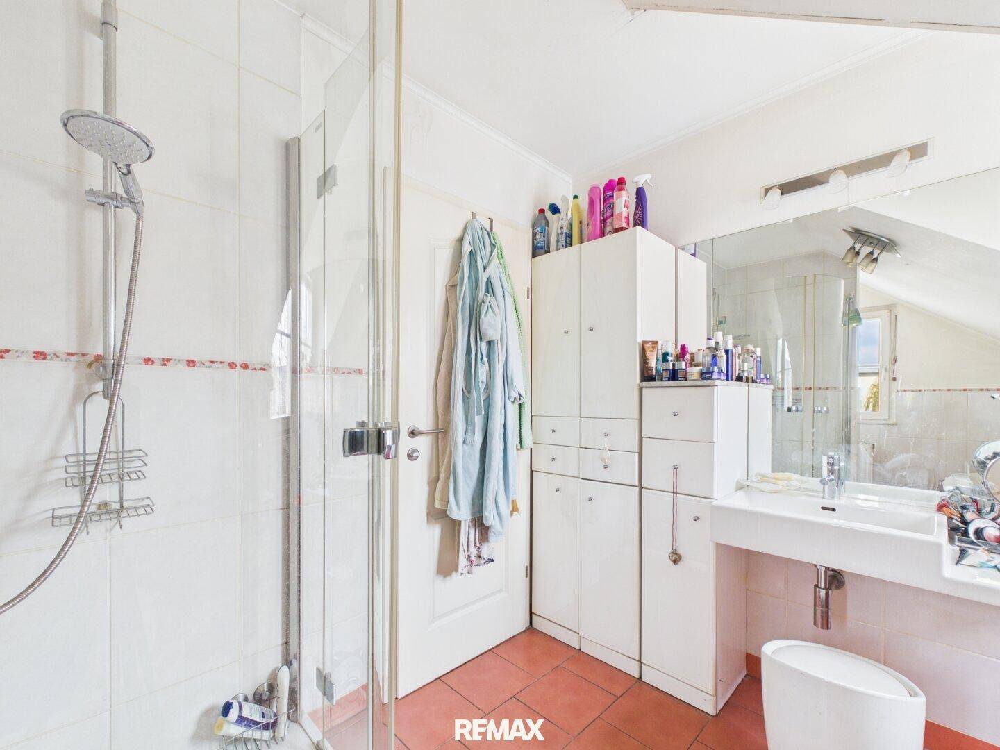 Badezimmer im Dachgeschoss mit Dusche, Waschbecken und Spiegelschrank.
