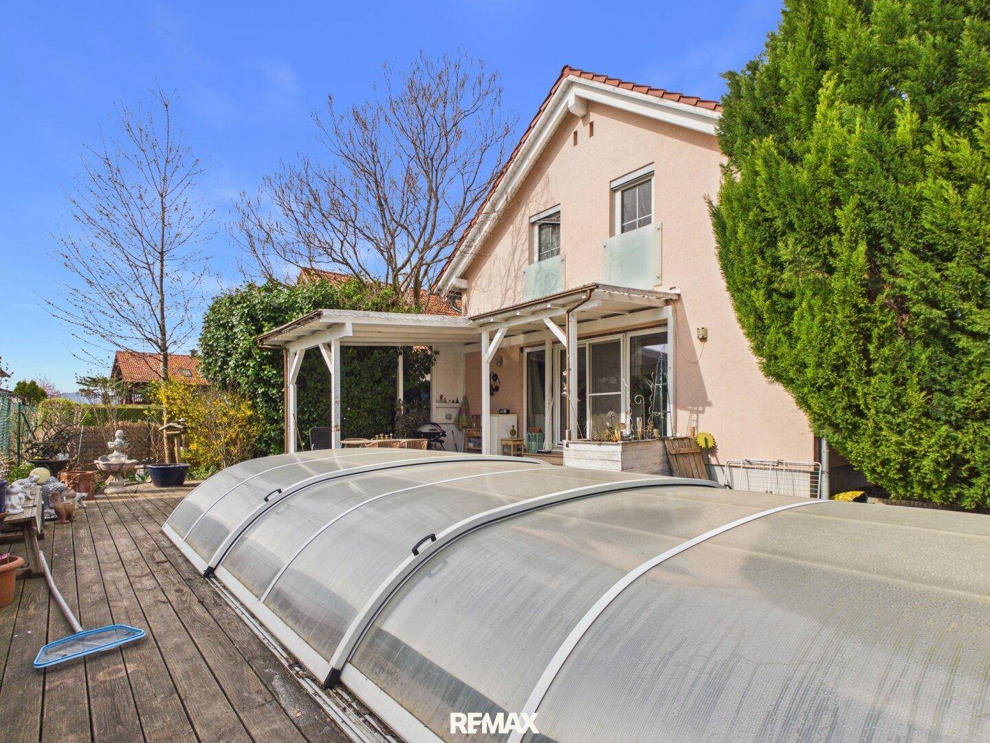 Großer Gartenbereich mit Holzterrasse, Poolabdeckung und überdachtem Essbereich.