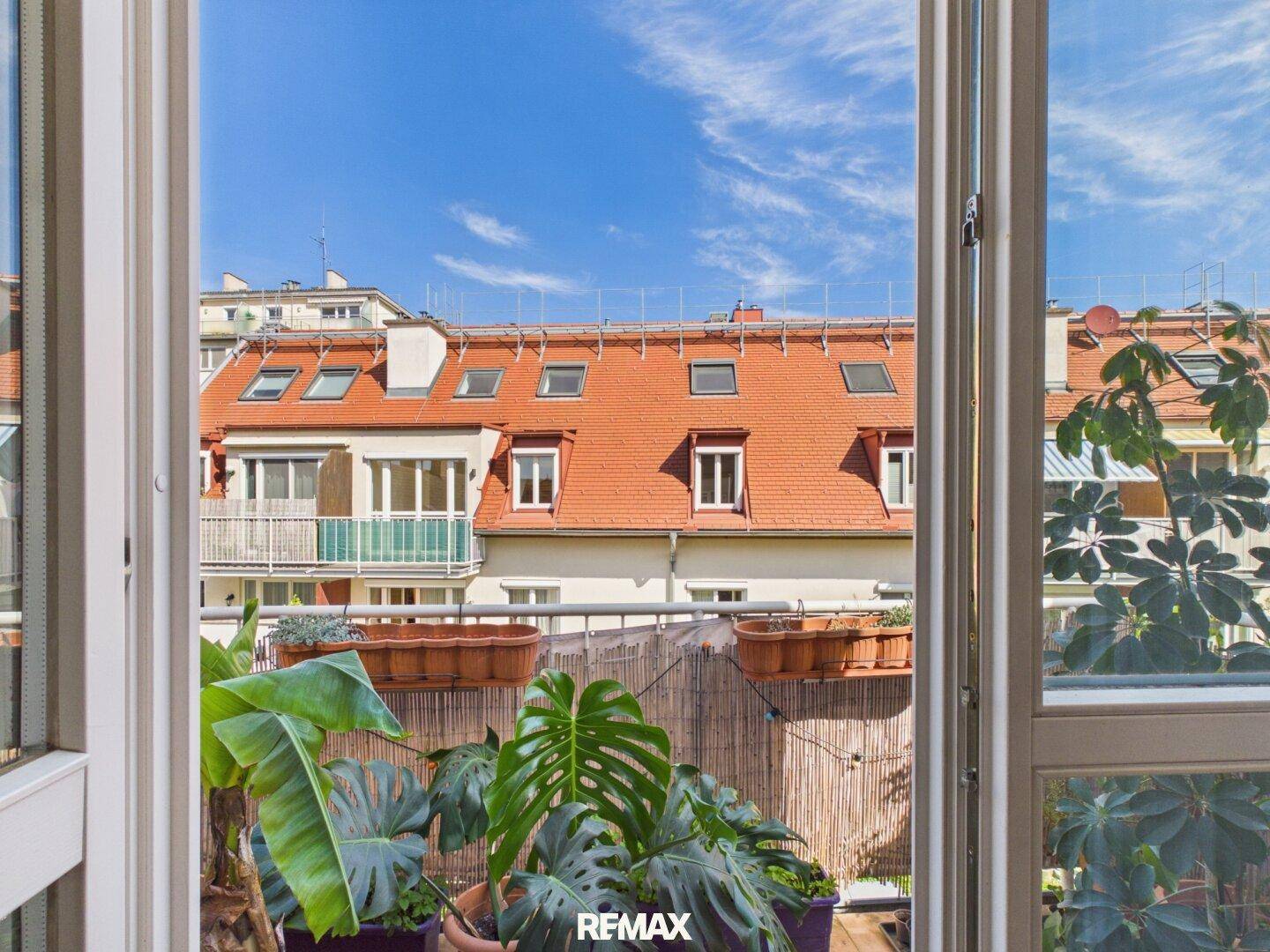 Blick vom Balkon auf benachbarte Gebäude mit roten Ziegeldächern und weiteren Balkonen.
