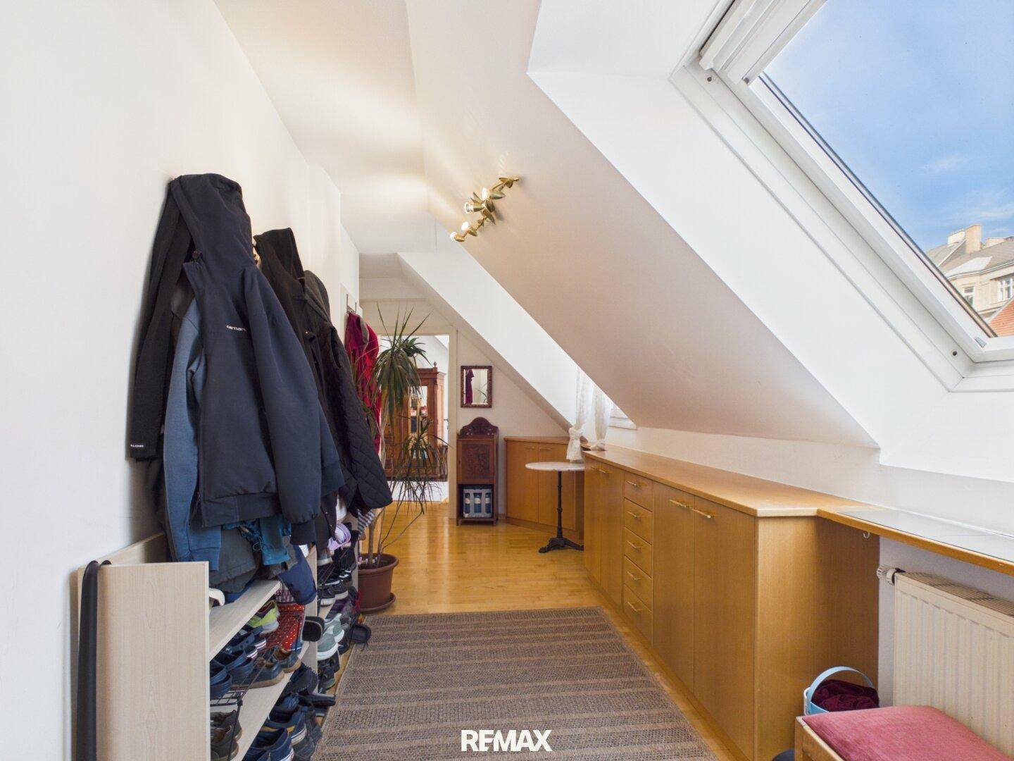 Dachgeschossflur mit schräger Decke, Dachfenster und praktischen Einbauschränken.