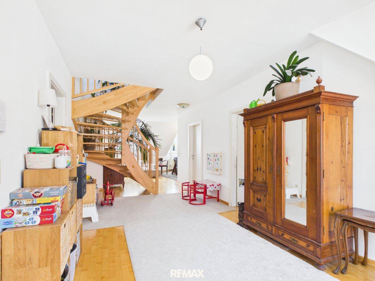 Geräumiger Flur mit eleganter Holztreppe, antiker Garderobe und hellem Ambiente.