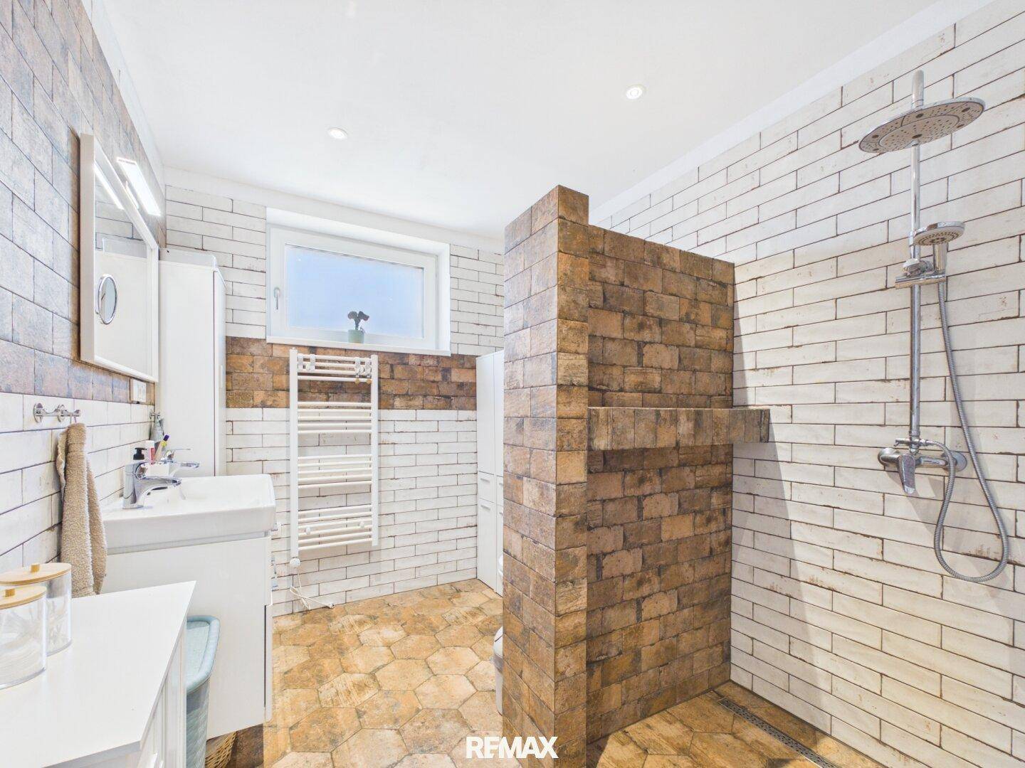 Modernes Badezimmer mit begehbarer Dusche, Ziegelwandakzenten und Fenster für Tageslicht.