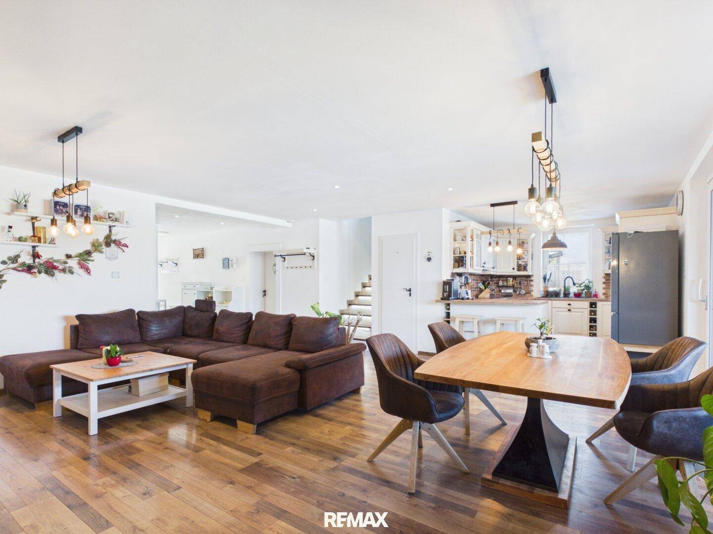 Geräumiger Wohn- und Essbereich mit Holzboden, großer Couch und modernem Esstisch.