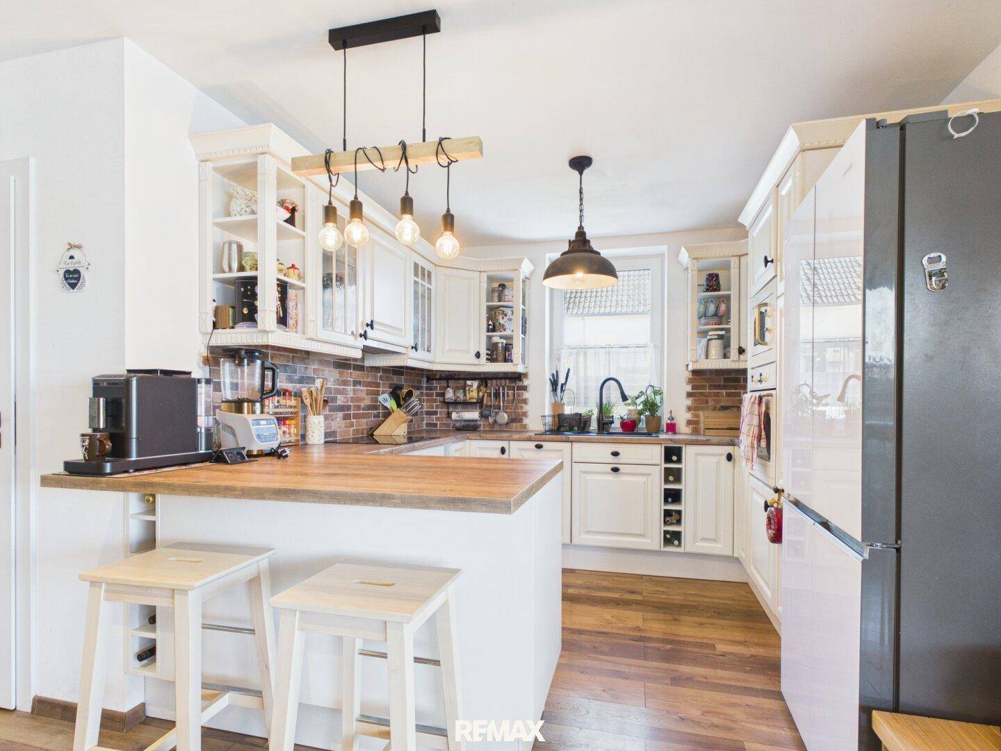 Helle Einbauküche im Landhausstil mit Holztheke, Backsteinakzenten und modernen Geräten.
