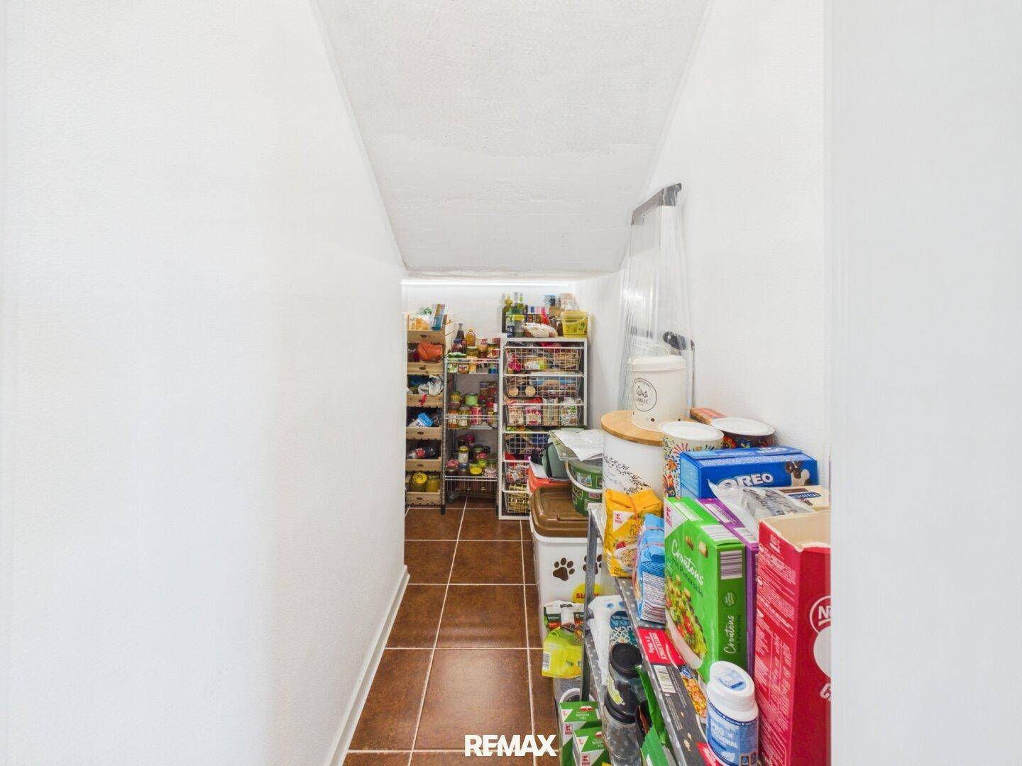 Praktische Speisekammer mit Regalen für Vorräte und Fliesenboden.