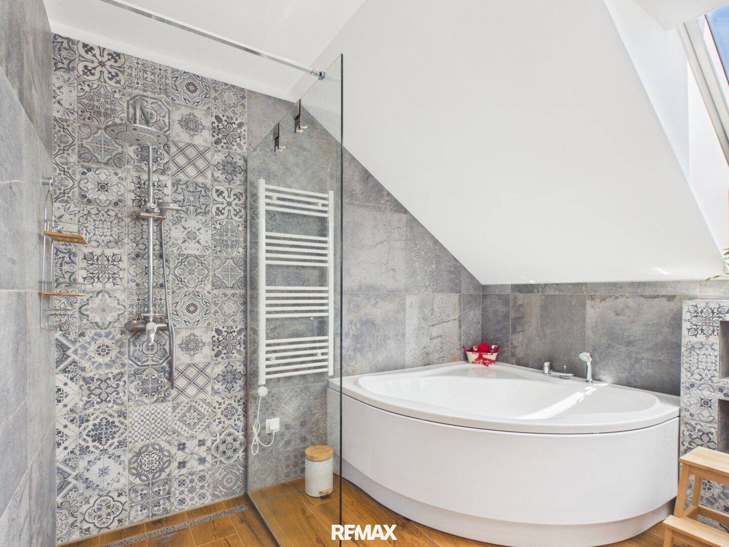 Geräumiges Badezimmer im Dachgeschoss mit Eckbadewanne, Dusche und gemusterten Fliesen.