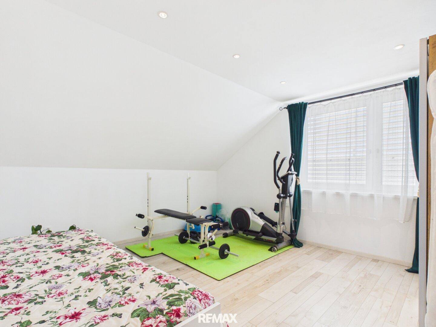 Schlafzimmer im Dachgeschoss, das als Fitnessraum genutzt wird, mit hellem Holzboden.