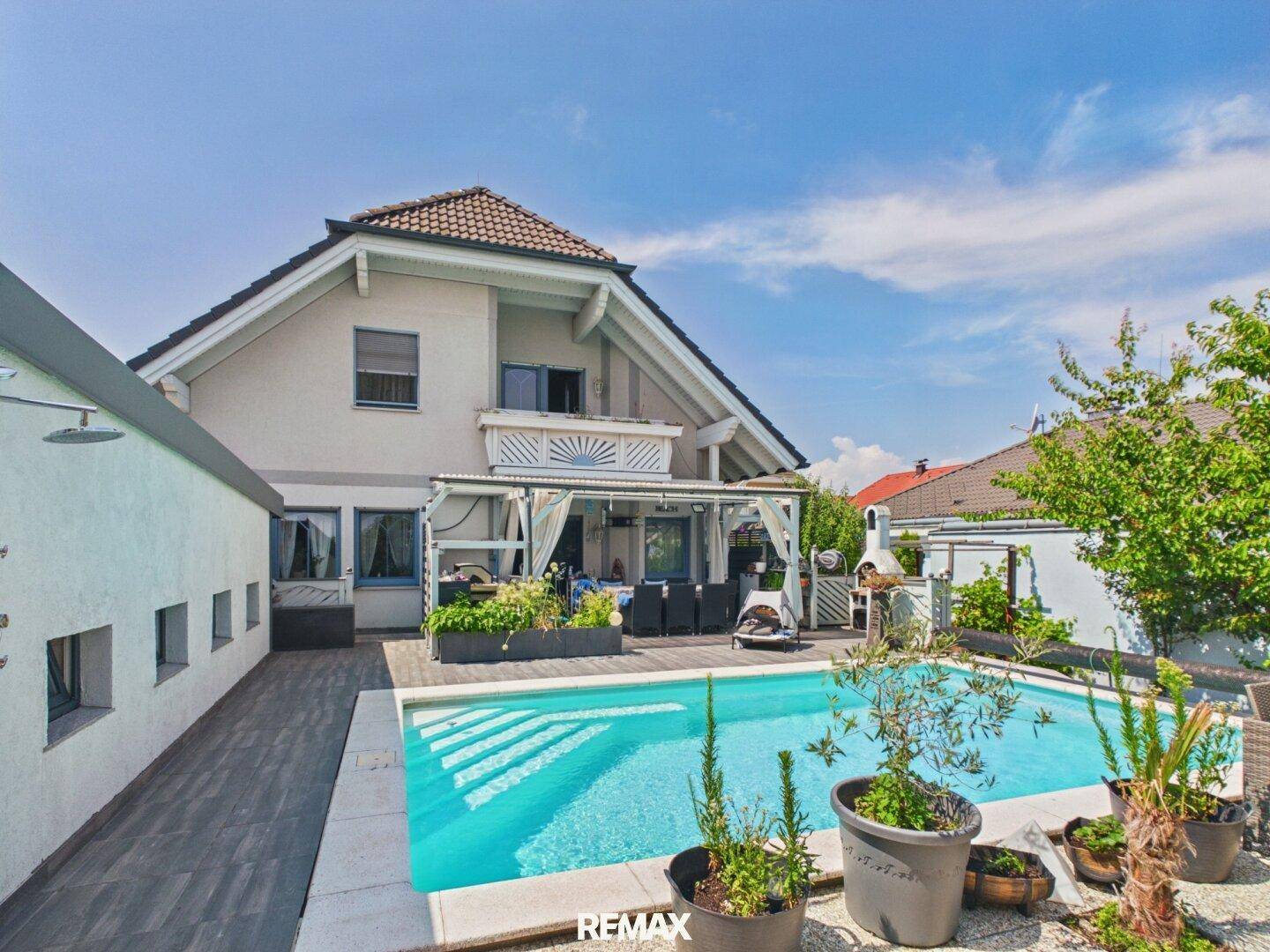 Weitläufiger Garten mit großem Swimmingpool, Liegeflächen und Grillbereich neben dem Poolhaus.
