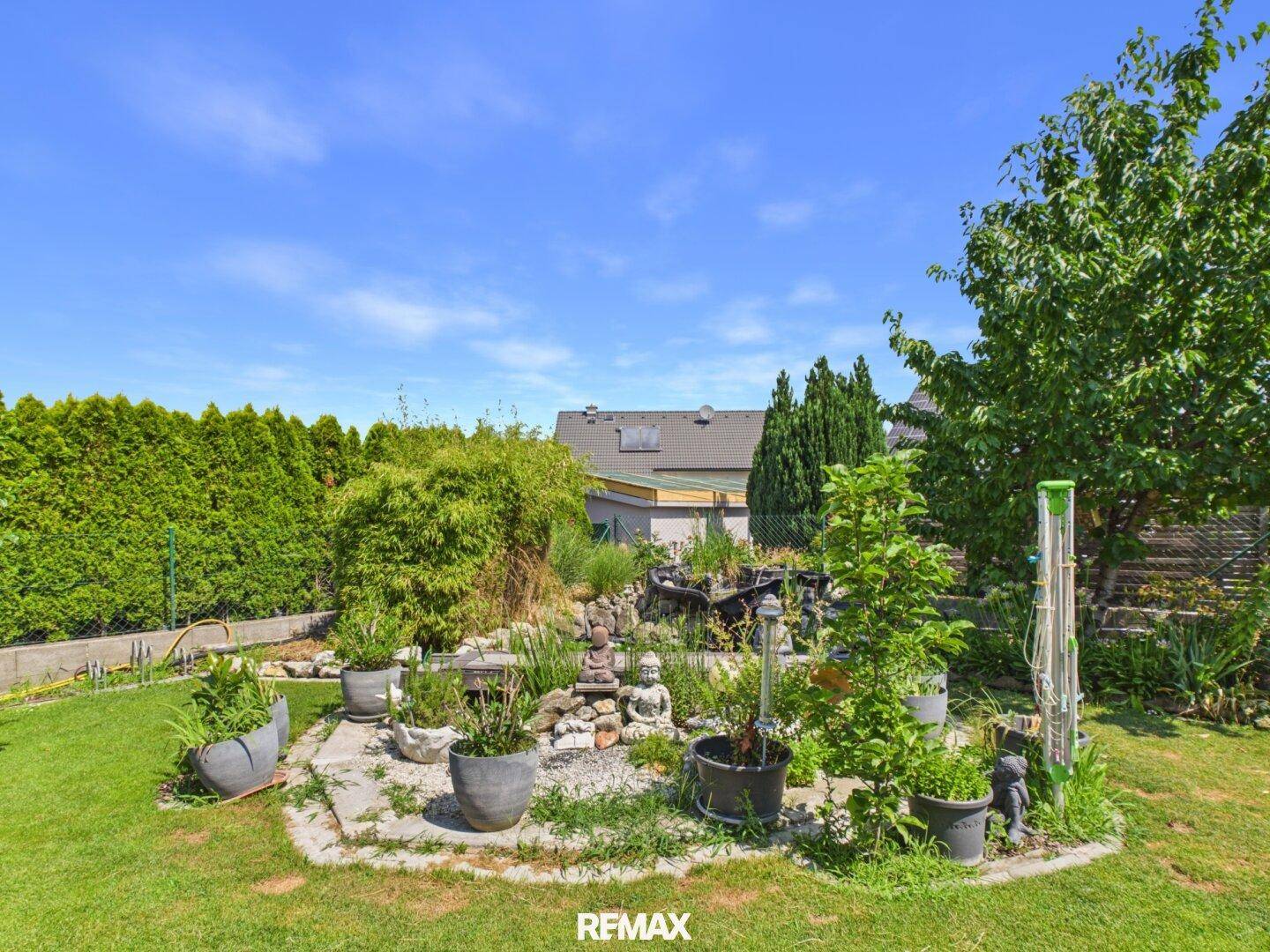 Idyllischer Gartenbereich mit Rasen, Zierpflanzen und dekorativen Elementen.