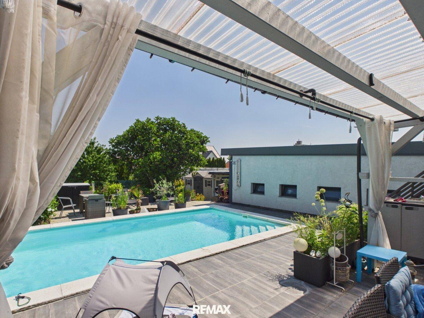 Überdachte Terrasse mit Blick auf den Swimmingpool und den gepflegten Gartenbereich.