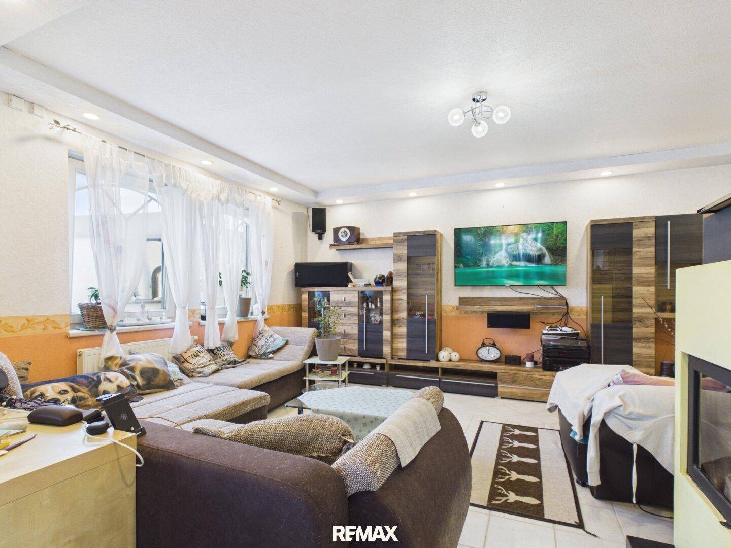 Gemütliches Wohnzimmer mit Kamin, großem Sofa und Unterhaltungselektronik.