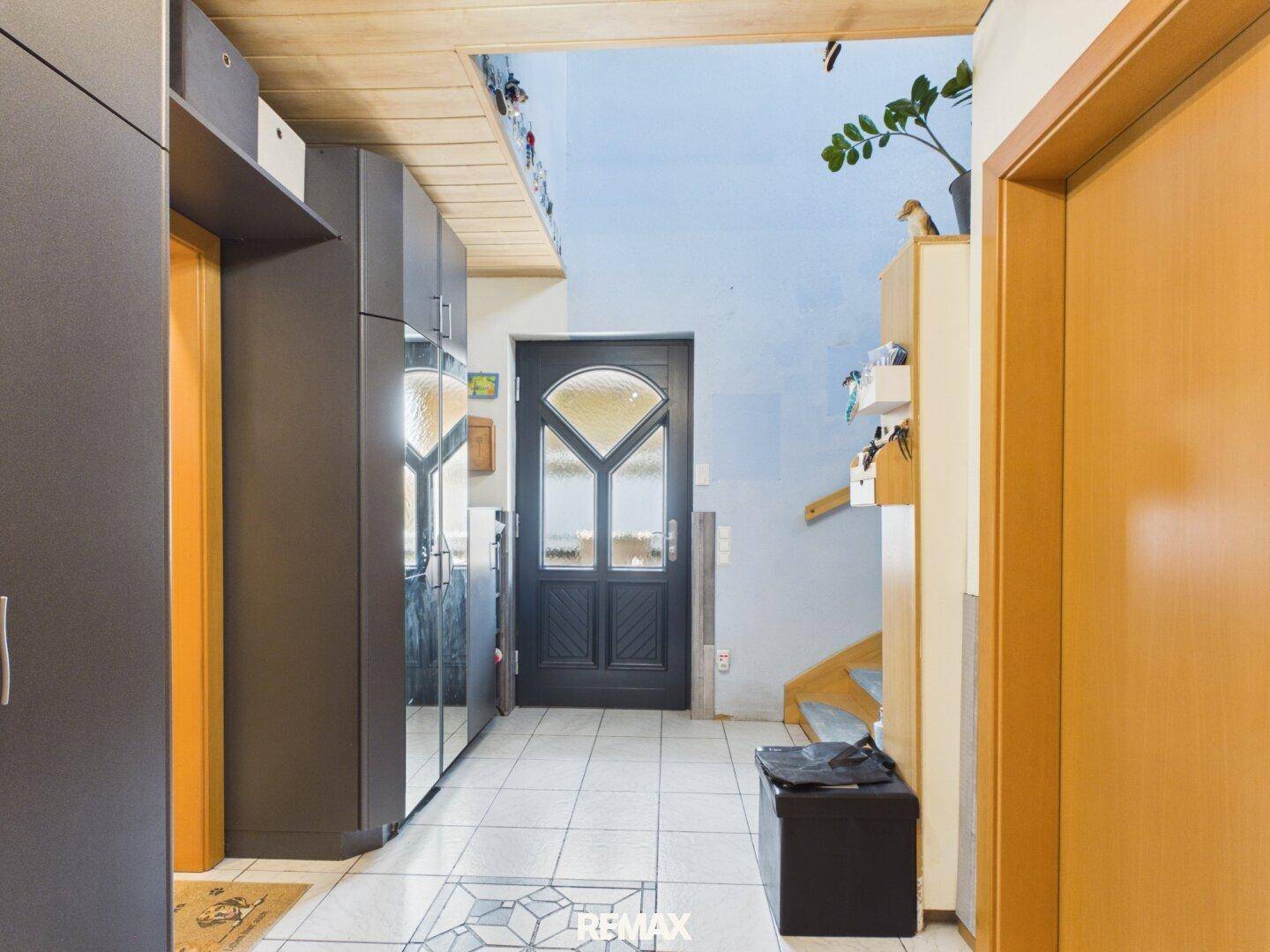 Heller Eingangsbereich mit Fliesenboden, Garderobe und Treppenaufgang.