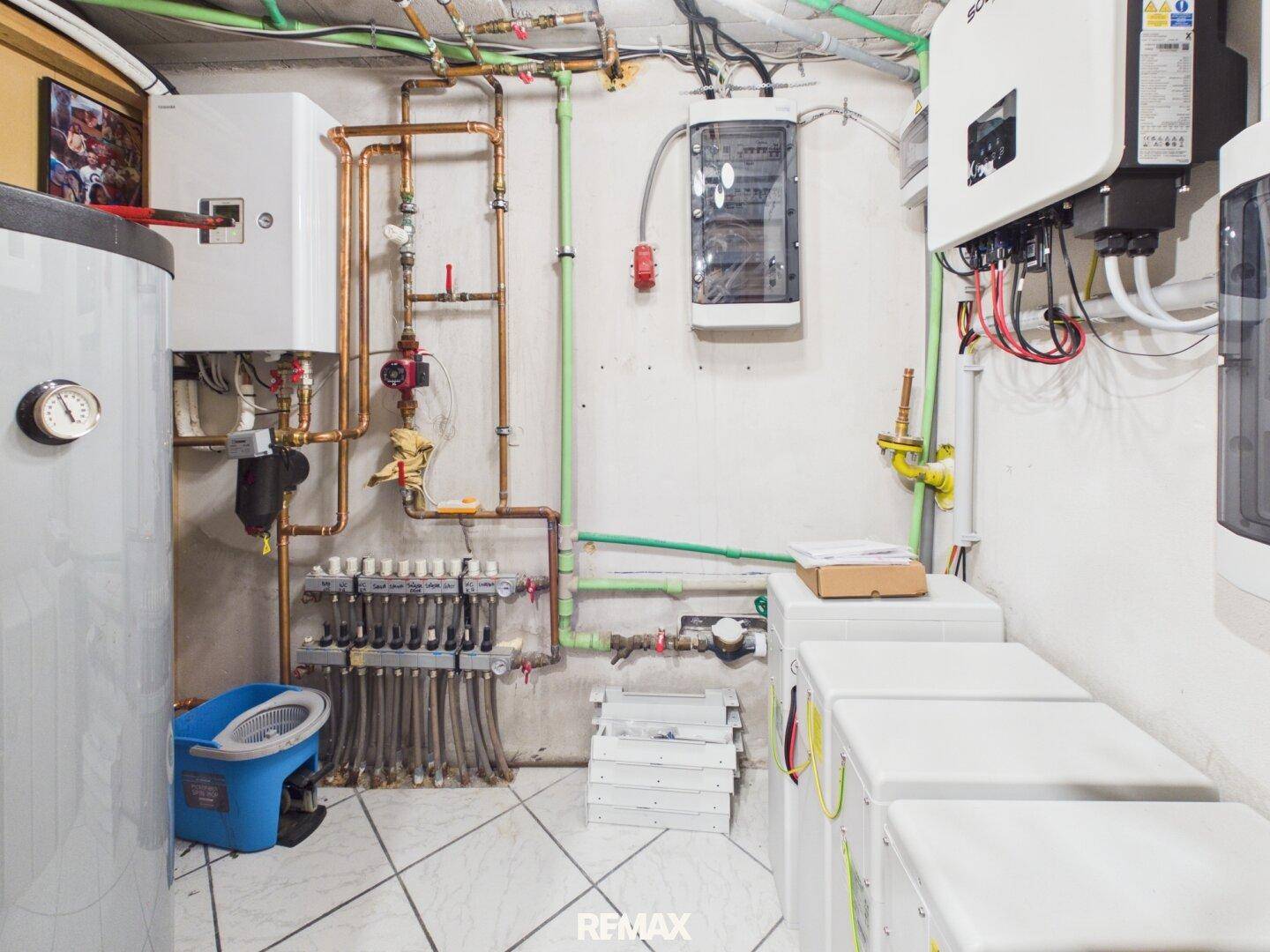 Technikraum mit Heizungsanlage, Warmwasserspeicher und Photovoltaik-Wechselrichtern.