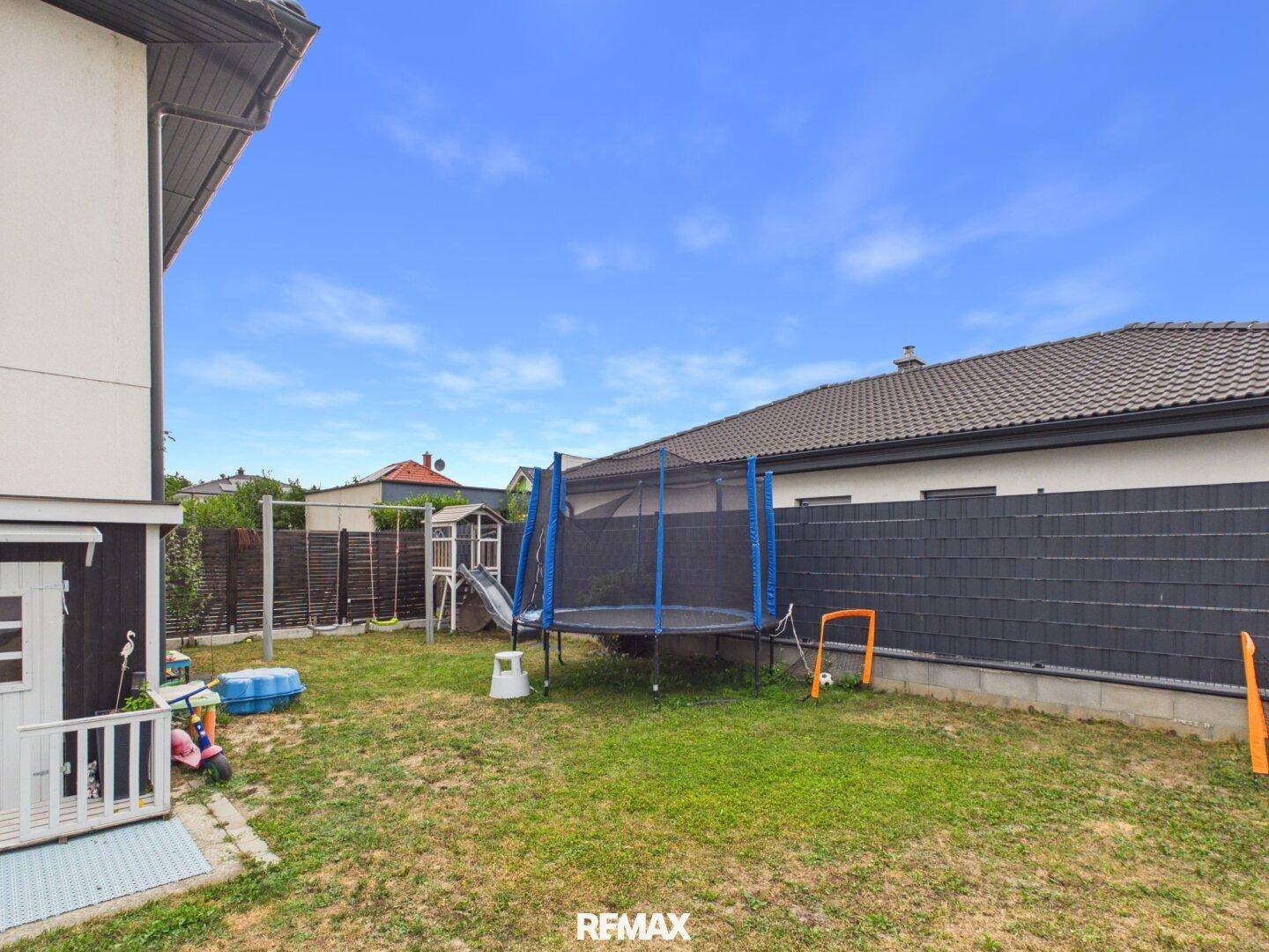 Kinderfreundlicher Gartenbereich mit Trampolin, Schaukel und Spielgeräten für aktive Kinder.