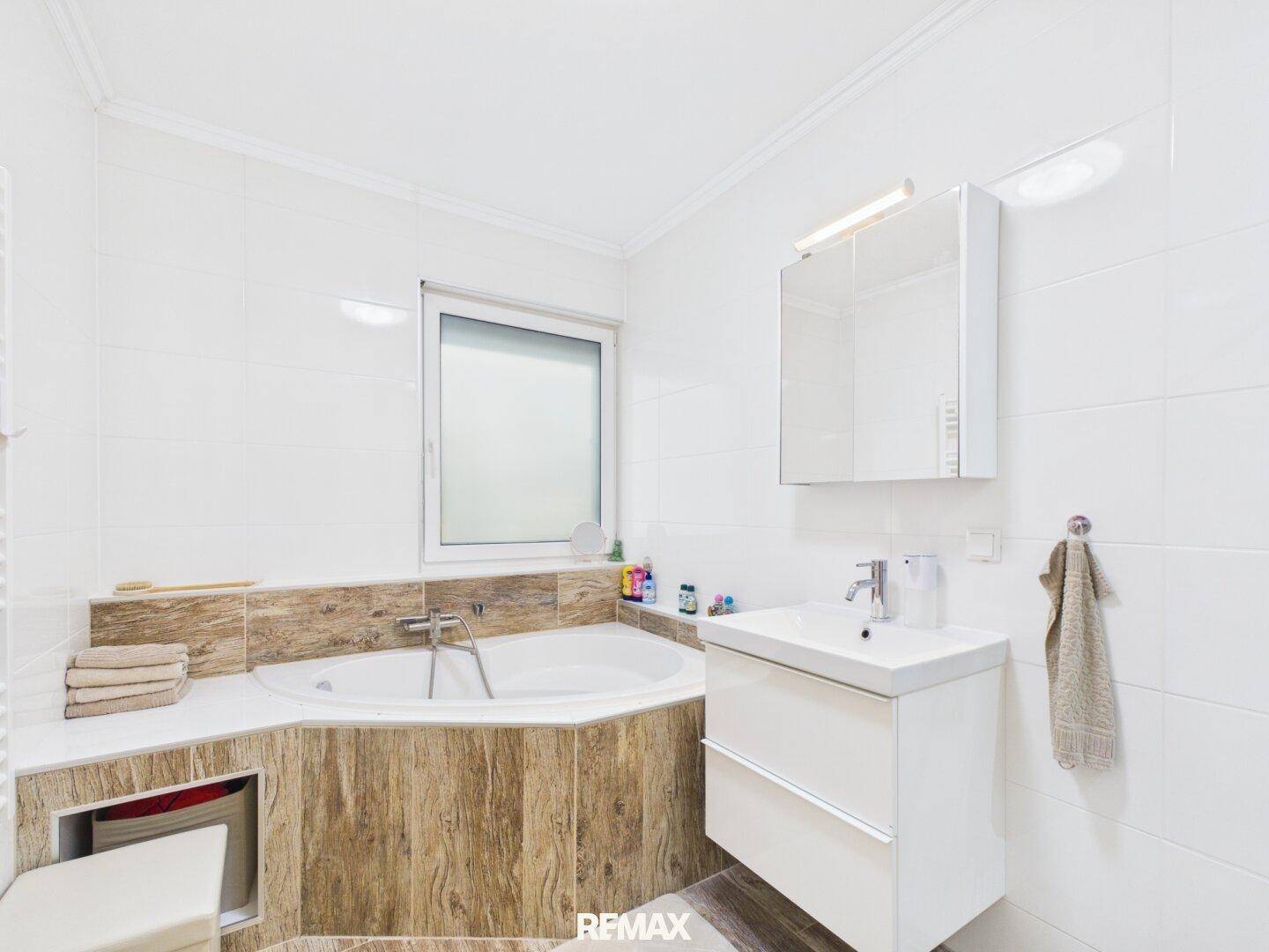 Modernes Badezimmer mit Eckbadewanne, Waschbecken und weißen Fliesen.