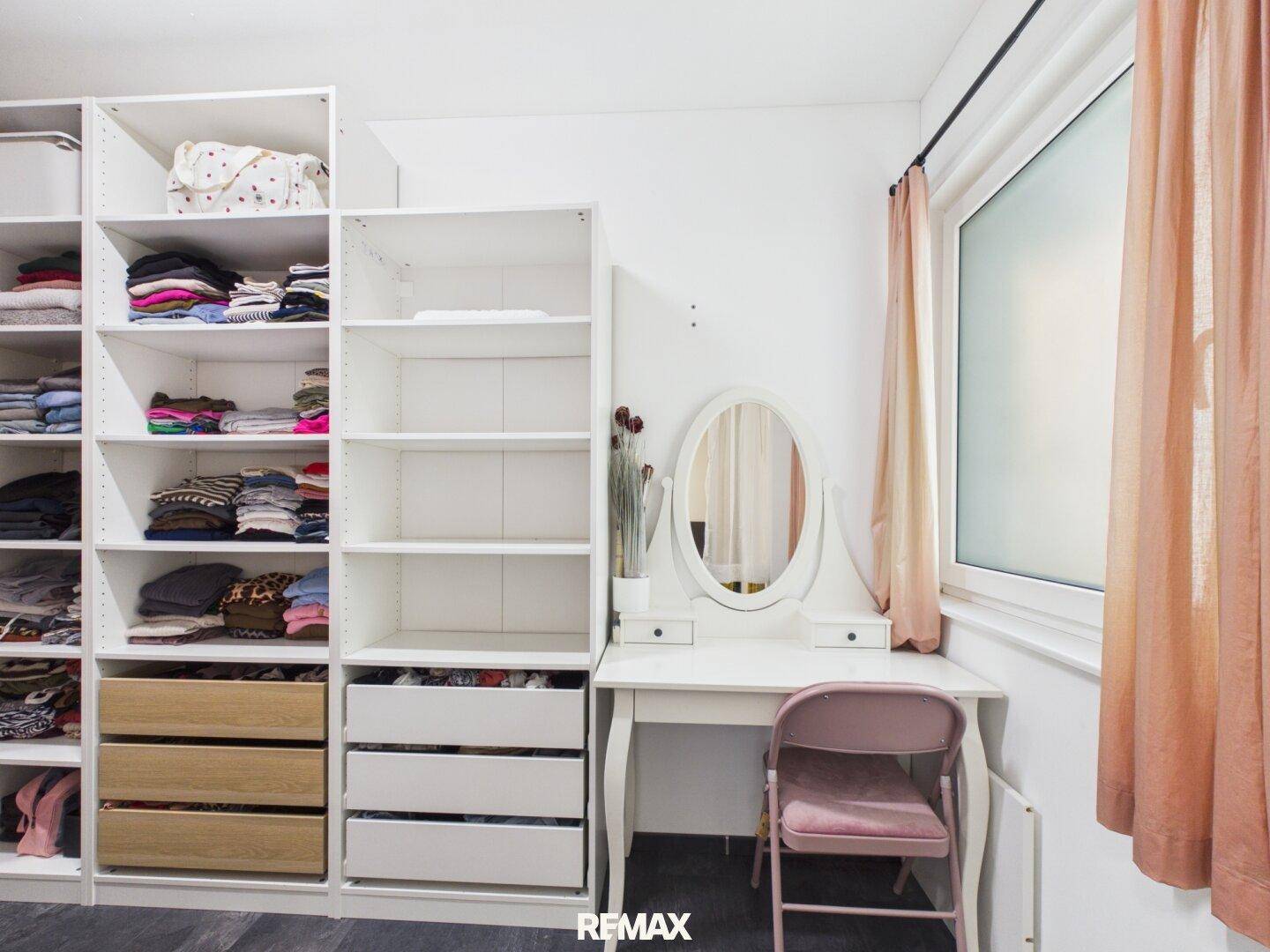 Praktischer begehbarer Kleiderschrank mit offenen Regalen und Schminktisch.