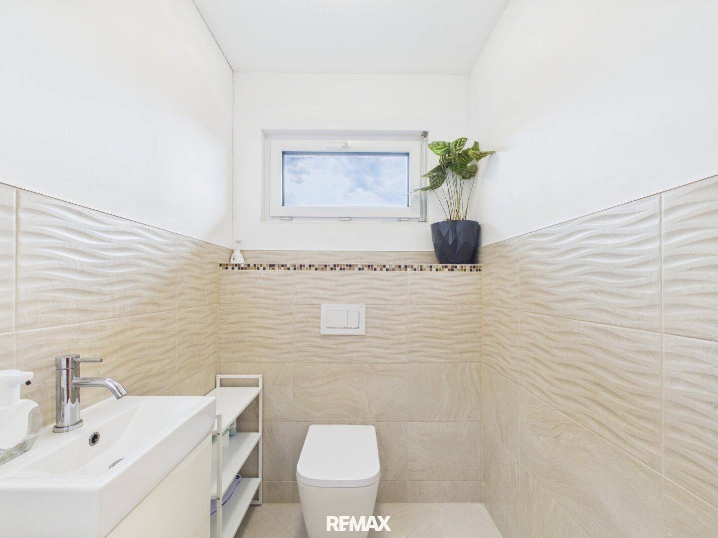 Modernes Gäste-WC mit beigefarbenen Wellenfliesen, wandhängendem WC und Fenster.