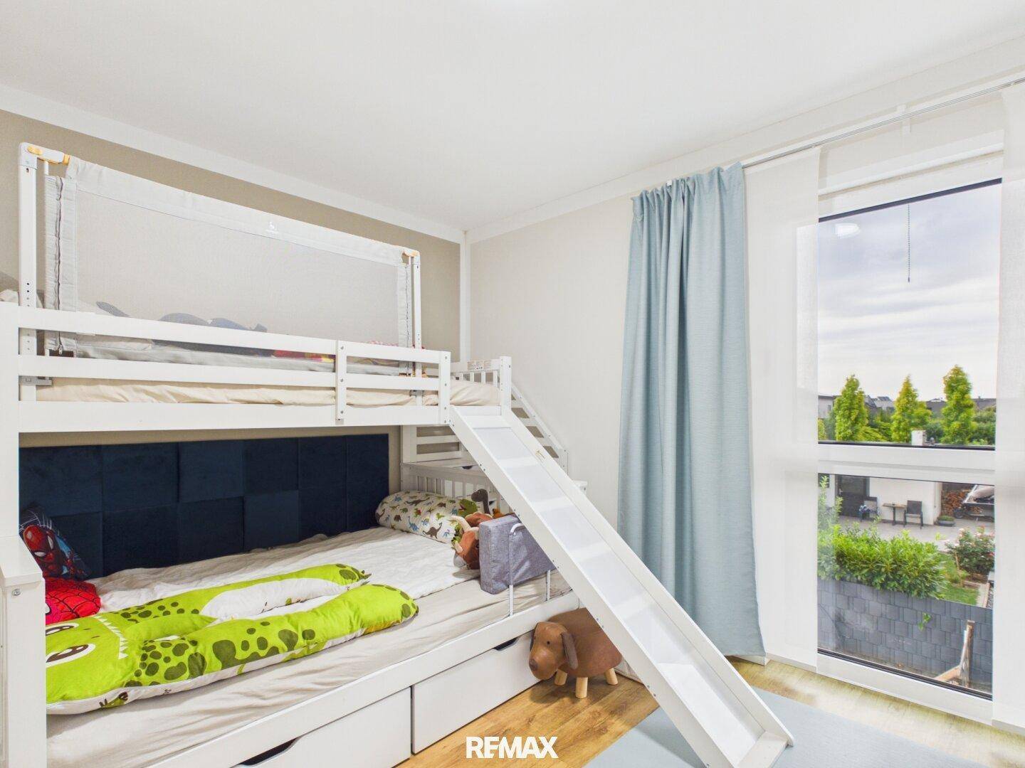 Kreatives Kinderzimmer mit Etagenbett, Rutsche und Blick ins Grüne.