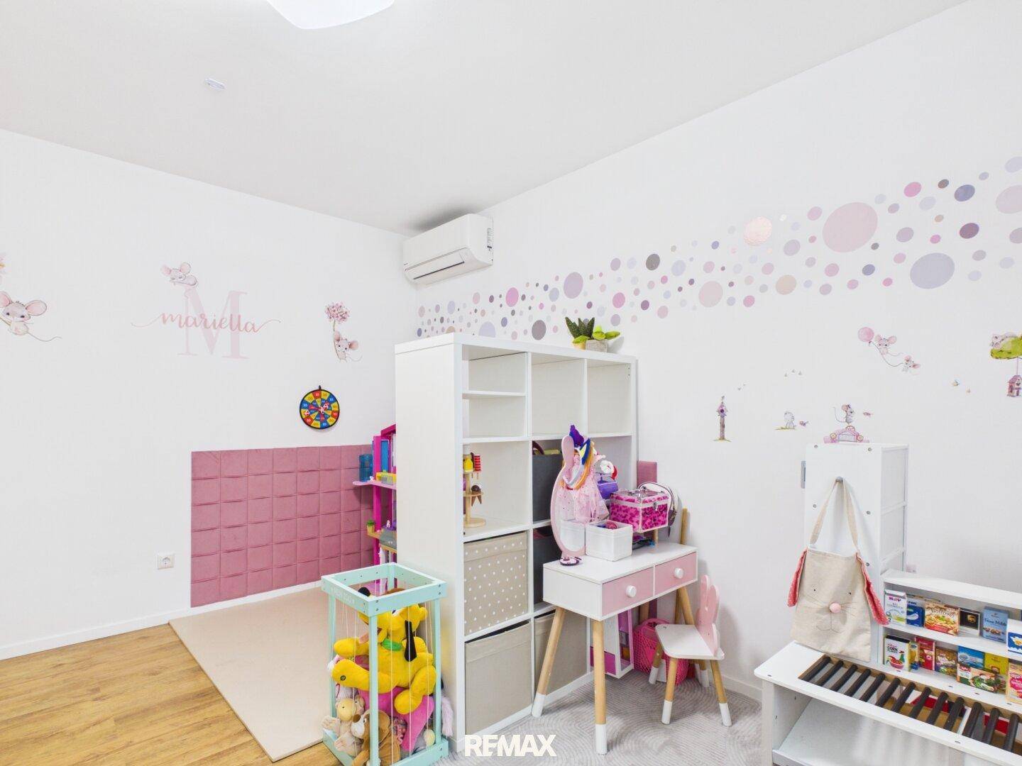 Freundliches Kinderzimmer mit Spielbereich, Schreibtisch und kreativer Wandgestaltung.