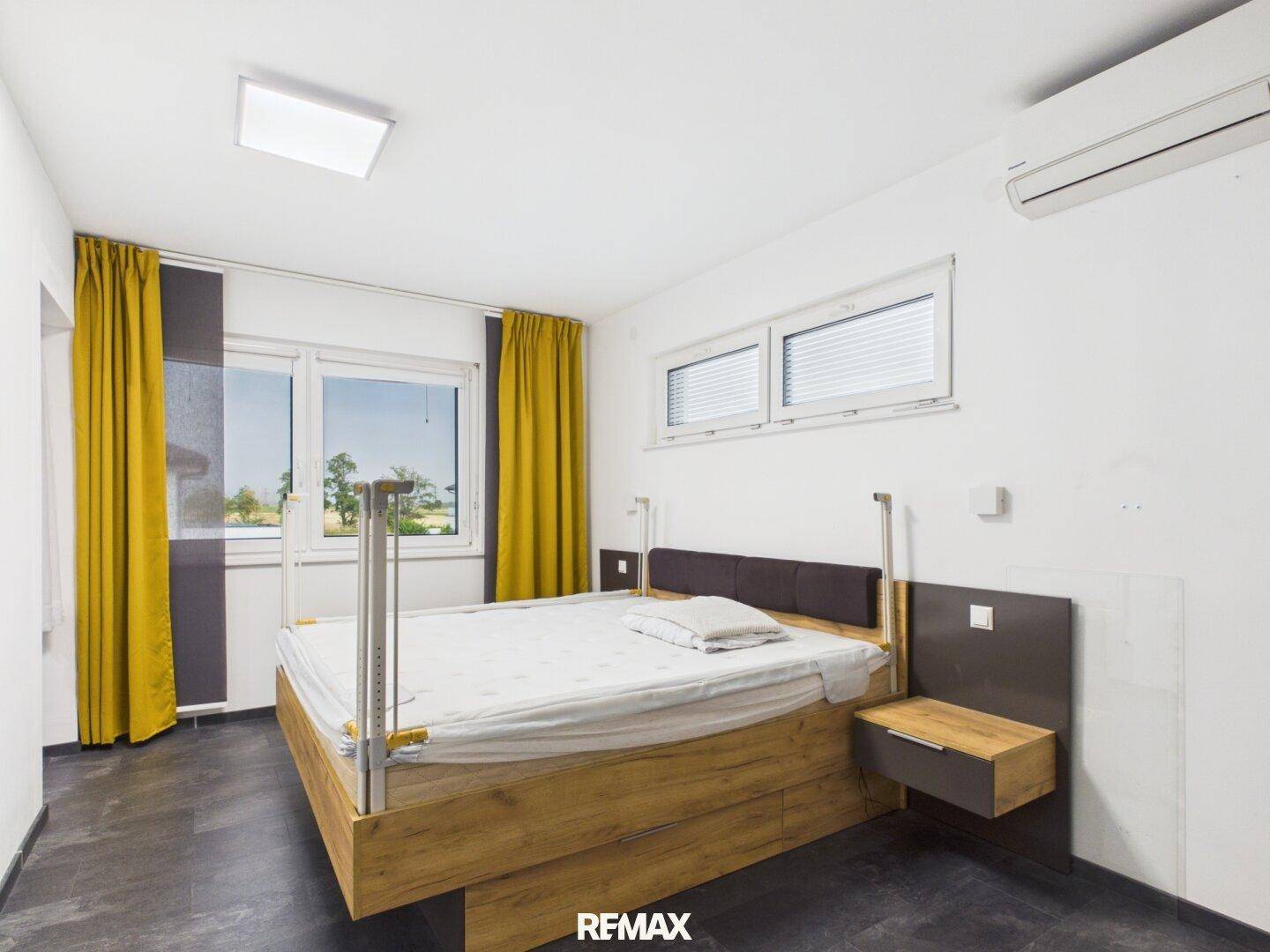 Geräumiges Schlafzimmer mit Doppelbett, Klimaanlage und großen Fenstern für viel Licht.