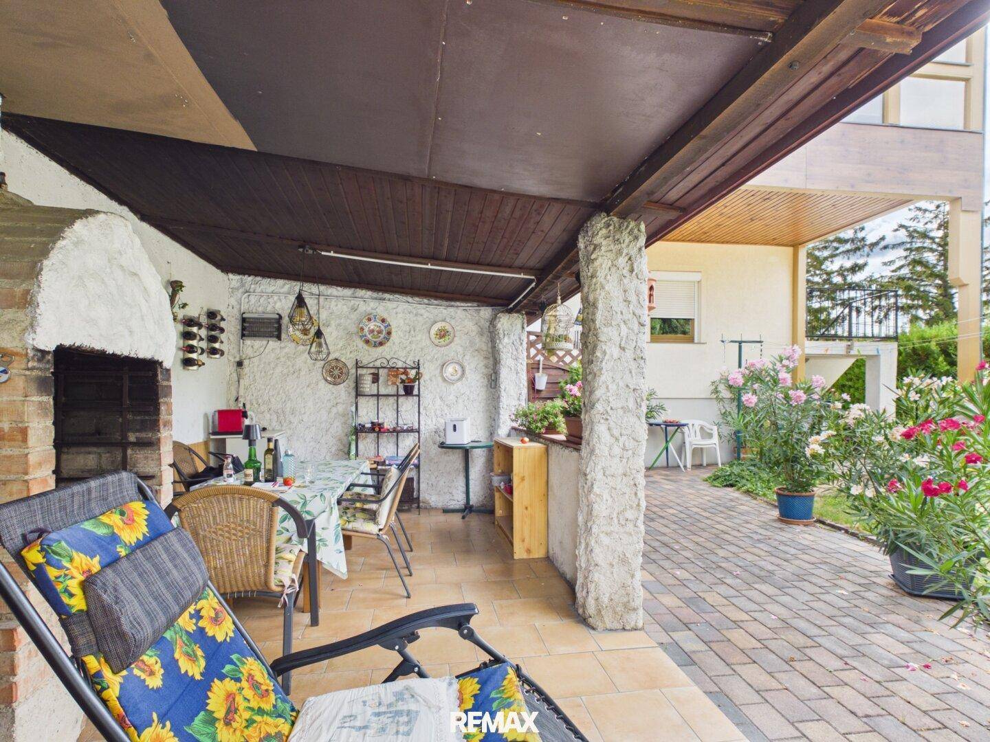 Gemütliche überdachte Terrasse mit Essbereich, Außenkamin und Blick auf den Garten.