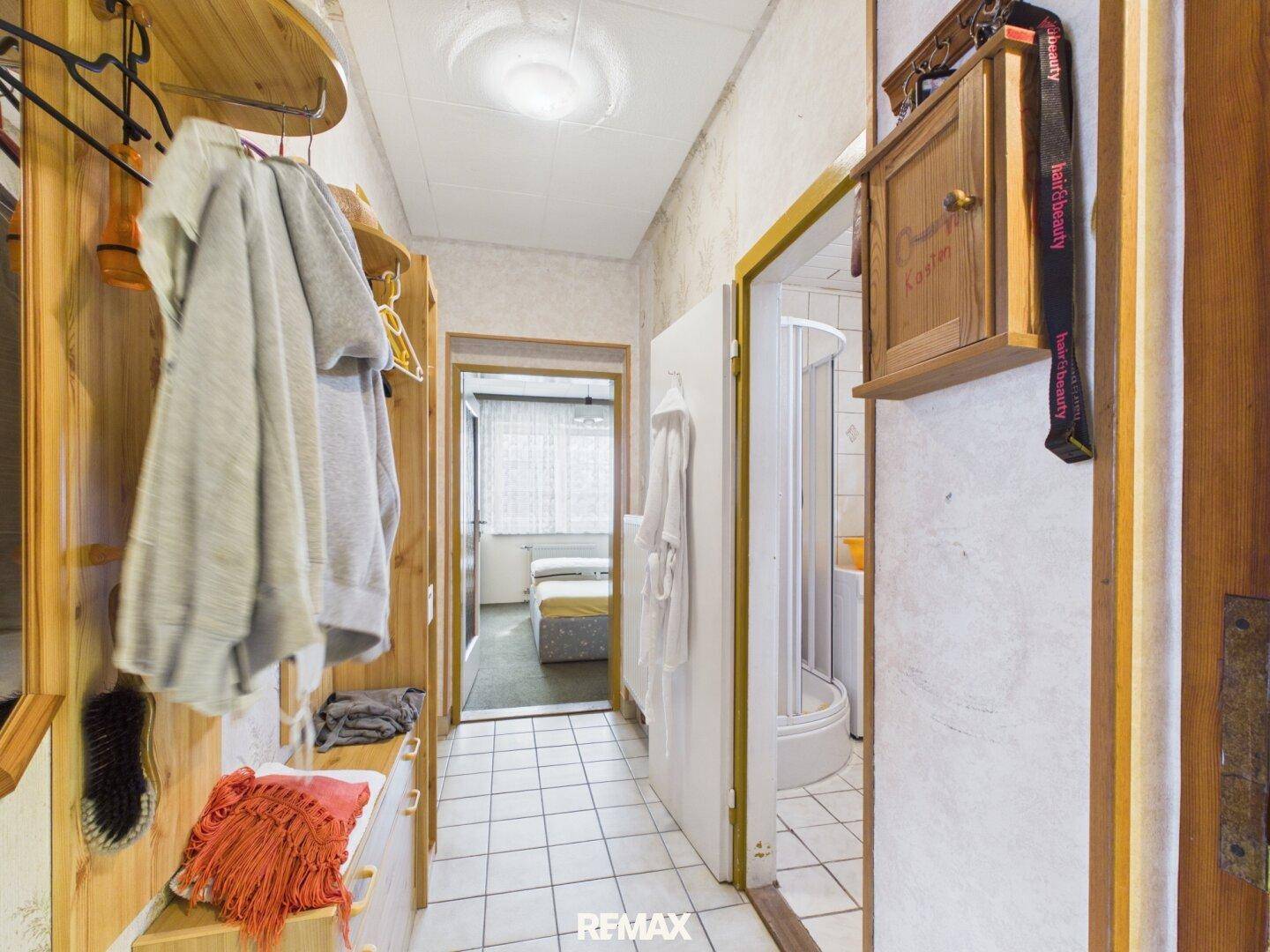 Schmaler Flur mit Holzvertäfelung, Garderobe und Zugang zu weiteren Räumen, darunter ein Badezimmer.