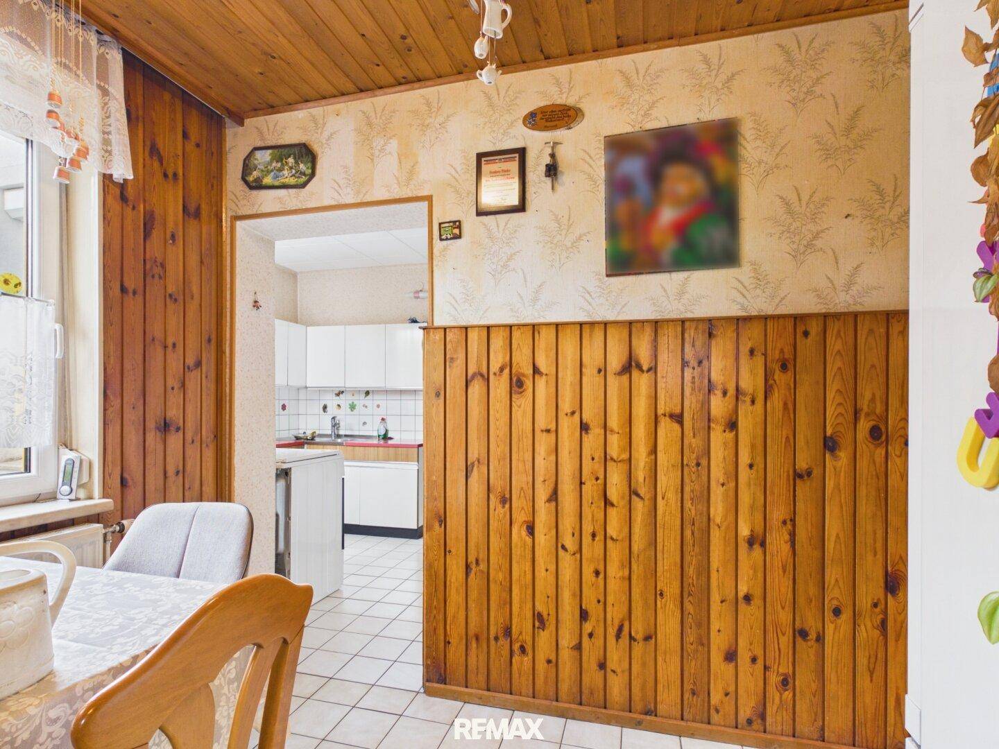 Essbereich mit Holzvertäfelung und Blick in eine angrenzende, hellere Küche, ideal für gemeinsame Mahlzeiten.