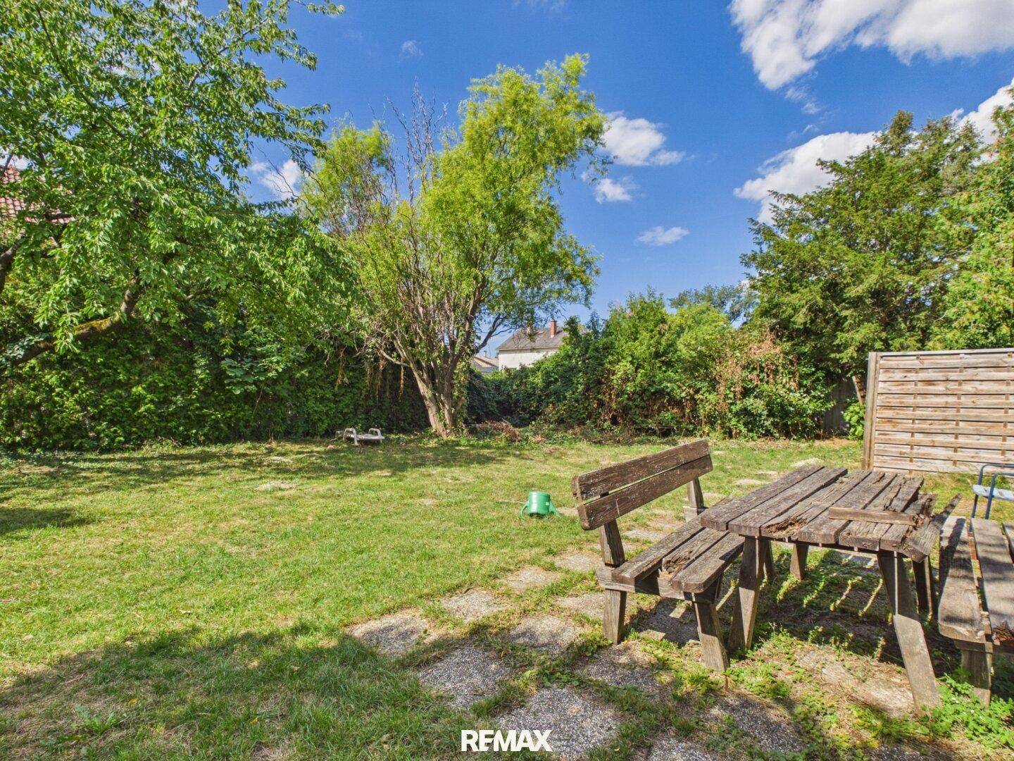 Rustikale Holzbank und Tisch im grünen Garten, ideal für entspannte Stunden im Freien.