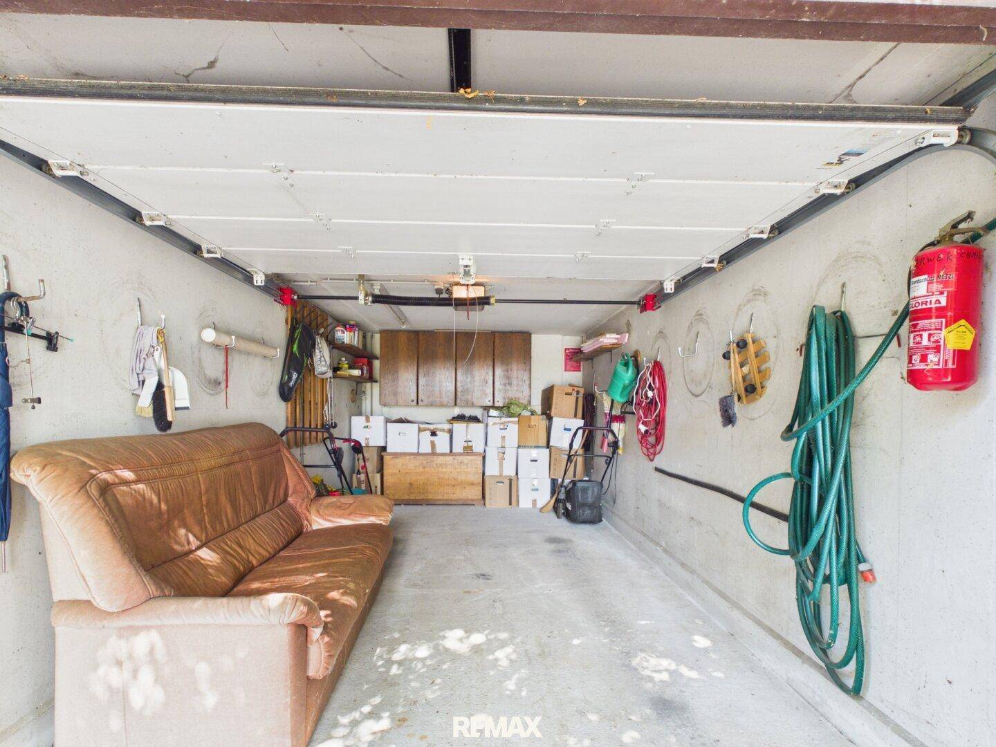 Innenansicht der Garage mit Stauraum, Werkzeugen und einer gemütlichen Couch.