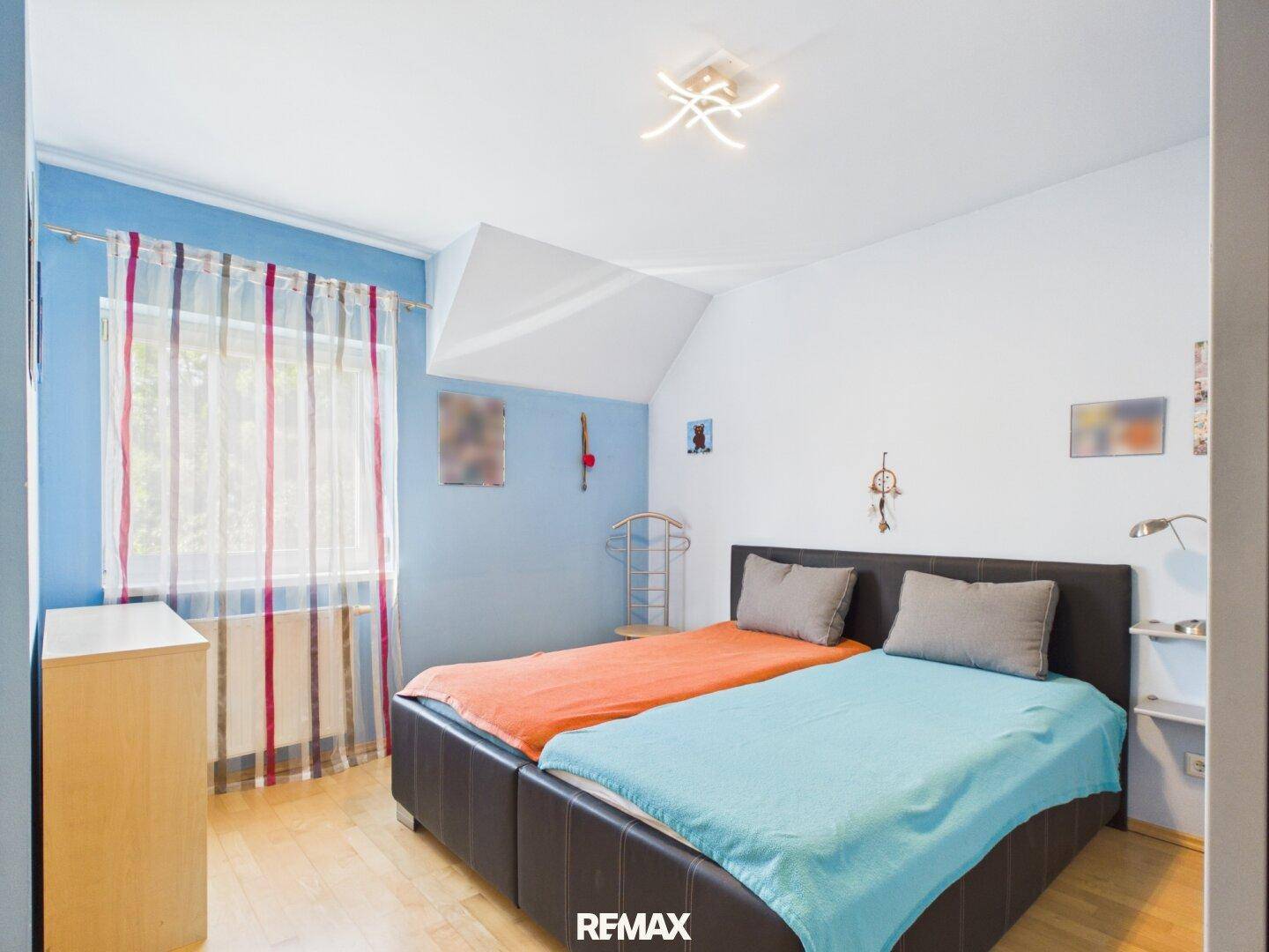 Schlafzimmer mit zwei Einzelbetten, blauen Wänden und Holzboden, gemütlich eingerichtet.