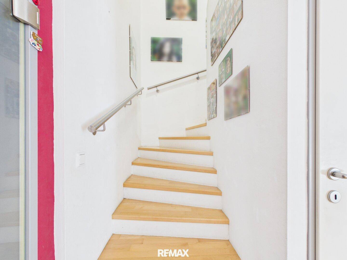 Helle Holztreppe mit Edelstahlgeländer führt in das Obergeschoss, modern und funktional.