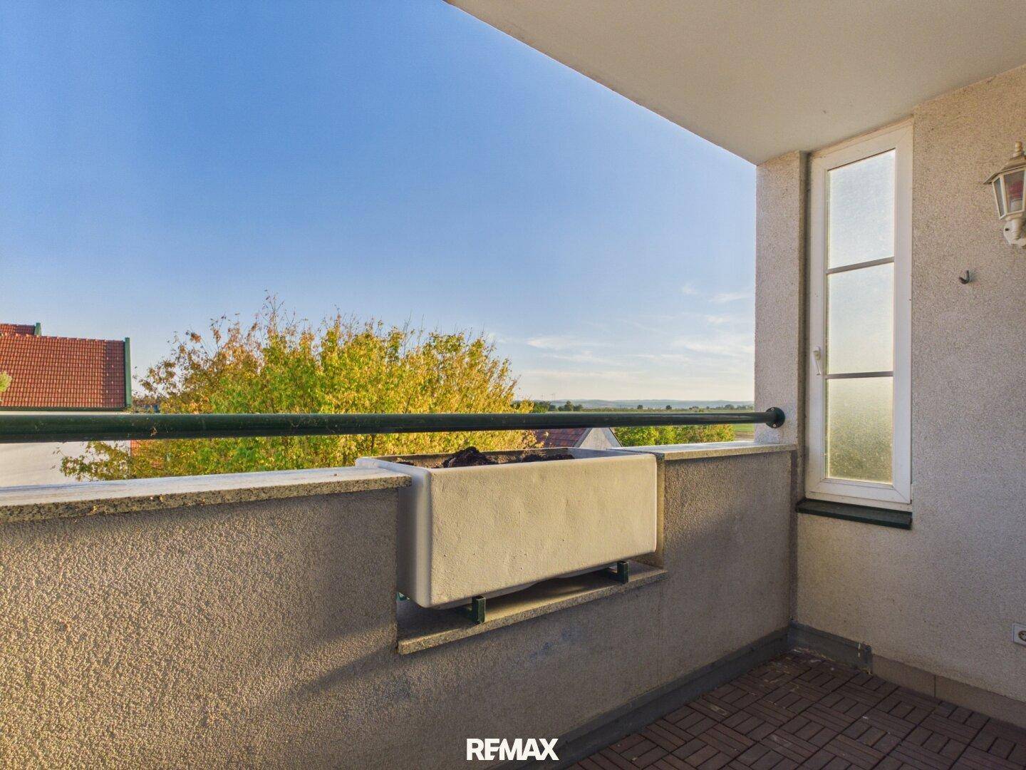 Balkon mit weitem Blick über die Landschaft und einen Blumenkasten, ideal zum Entspannen.
