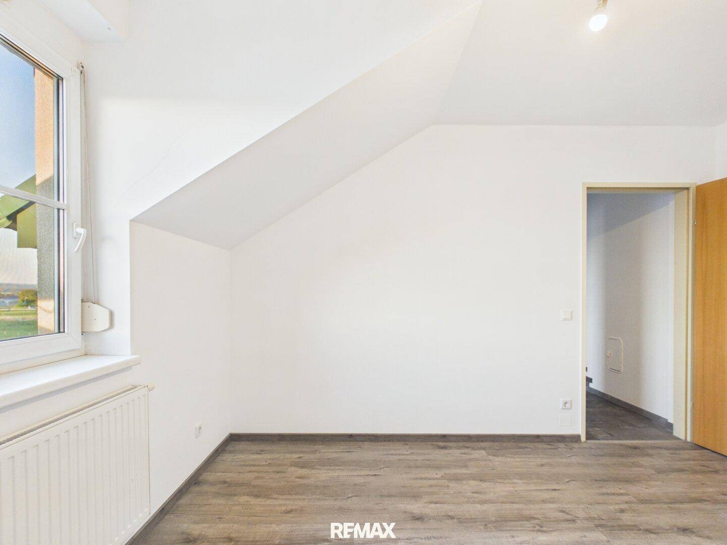 Geräumiges Schlafzimmer mit Laminatboden, weißen Wänden und Fenster, bietet viel Gestaltungspotenzial.